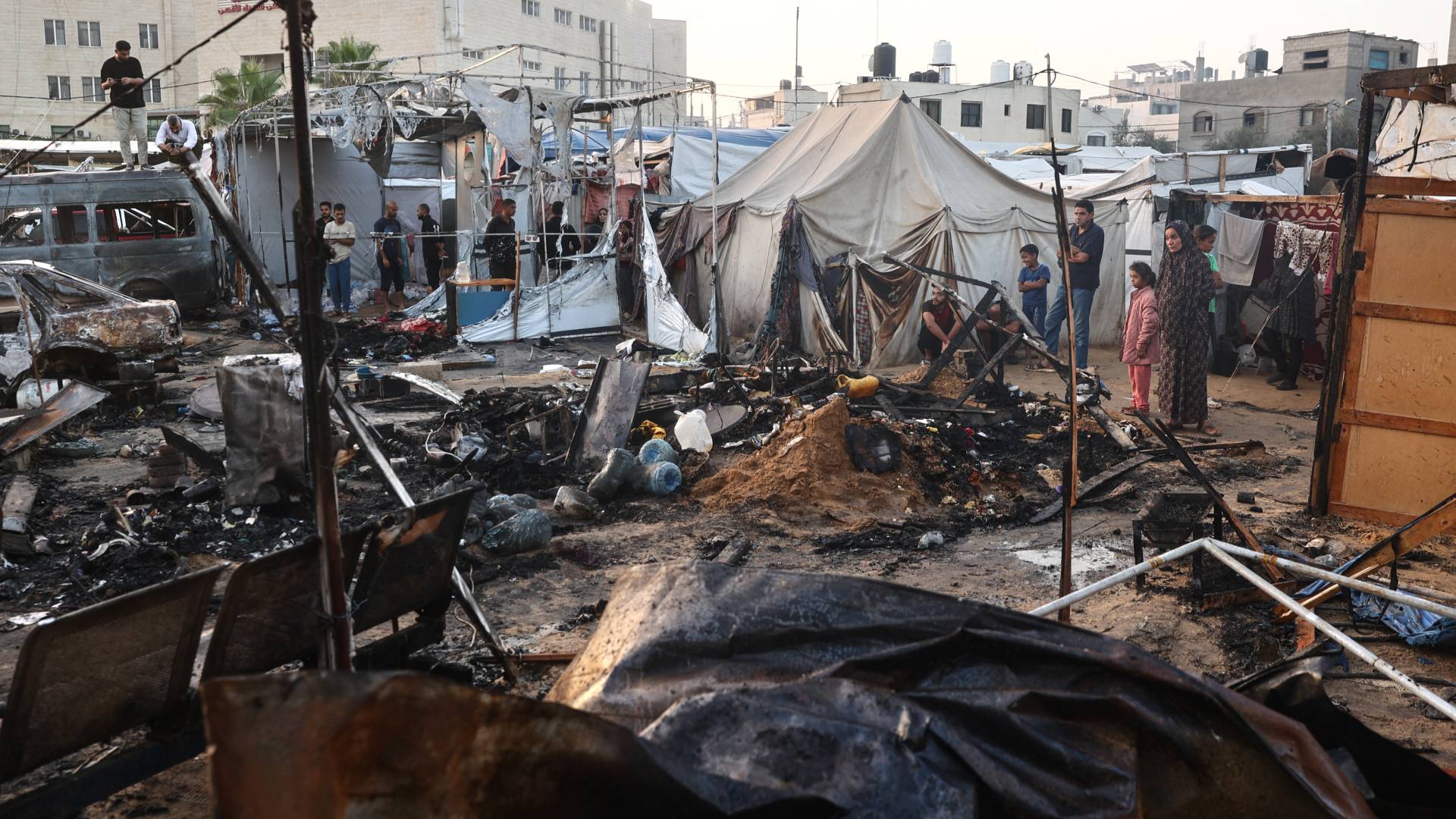 فلسطينيون يتحققون من الدمار الذي أعقب غارة لللاحتلال حول خيام النازحين داخل أسوار مستشفى شهداء الأقصى في دير البلح