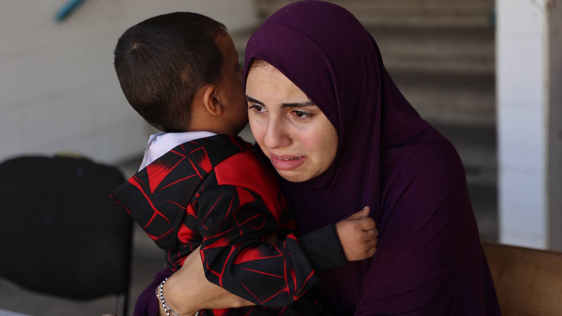 امرأة فلسطينية نازحة تحمل طفلا داخل مدرسة تابعة للأمم المتحدة تحولت إلى مأوى في مخيم الشاطئ للاجئين