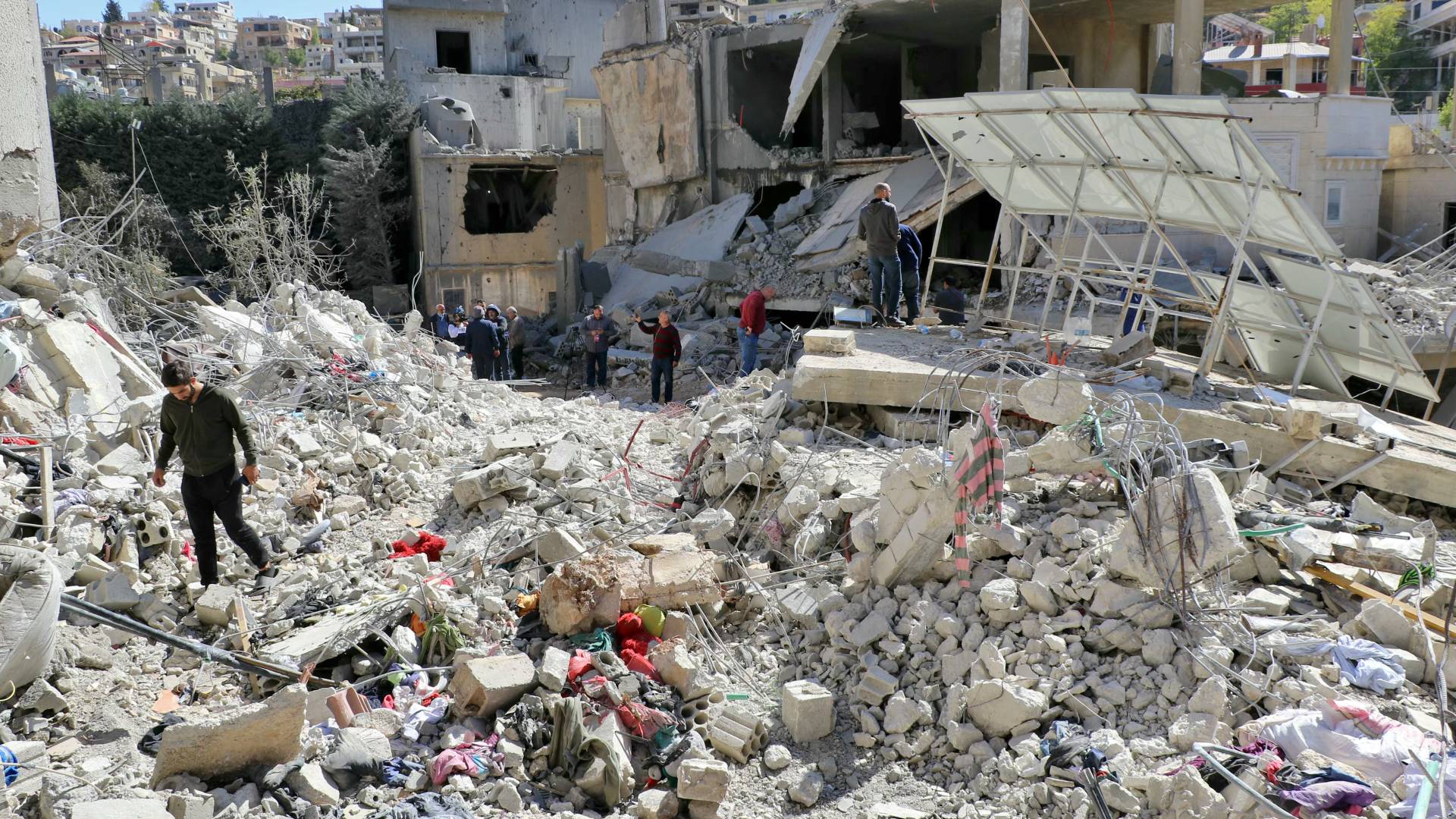 أشخاص يتفقدون الأضرار في موقع غارة جوية للاحتلال استهدفت قرية النبي شيث الشرقية