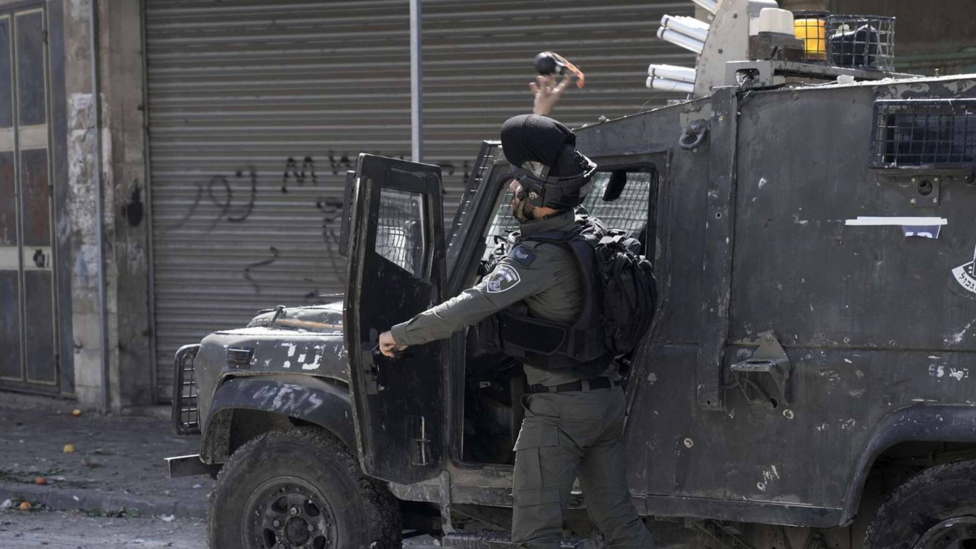 جندي من جيش الاحتلال يلقي قنابل باتجاه الفلسطينيين