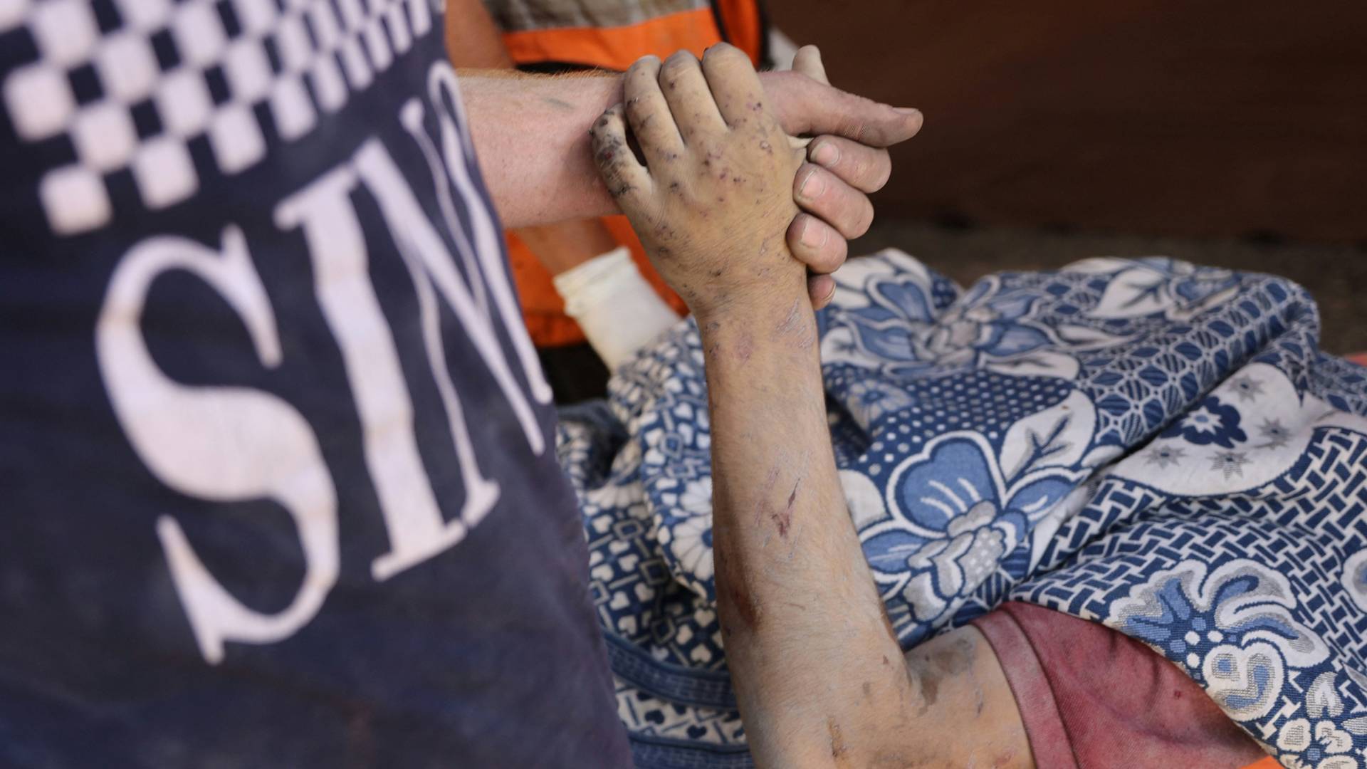 فلسطيني يمسك بيد أحد أفراد عائلته الشهيد