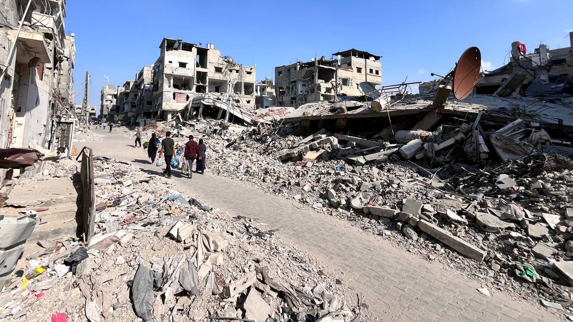 فلسطينيون يسيرون وسط الدمار في بيت لاهيا شمال قطاع غزة