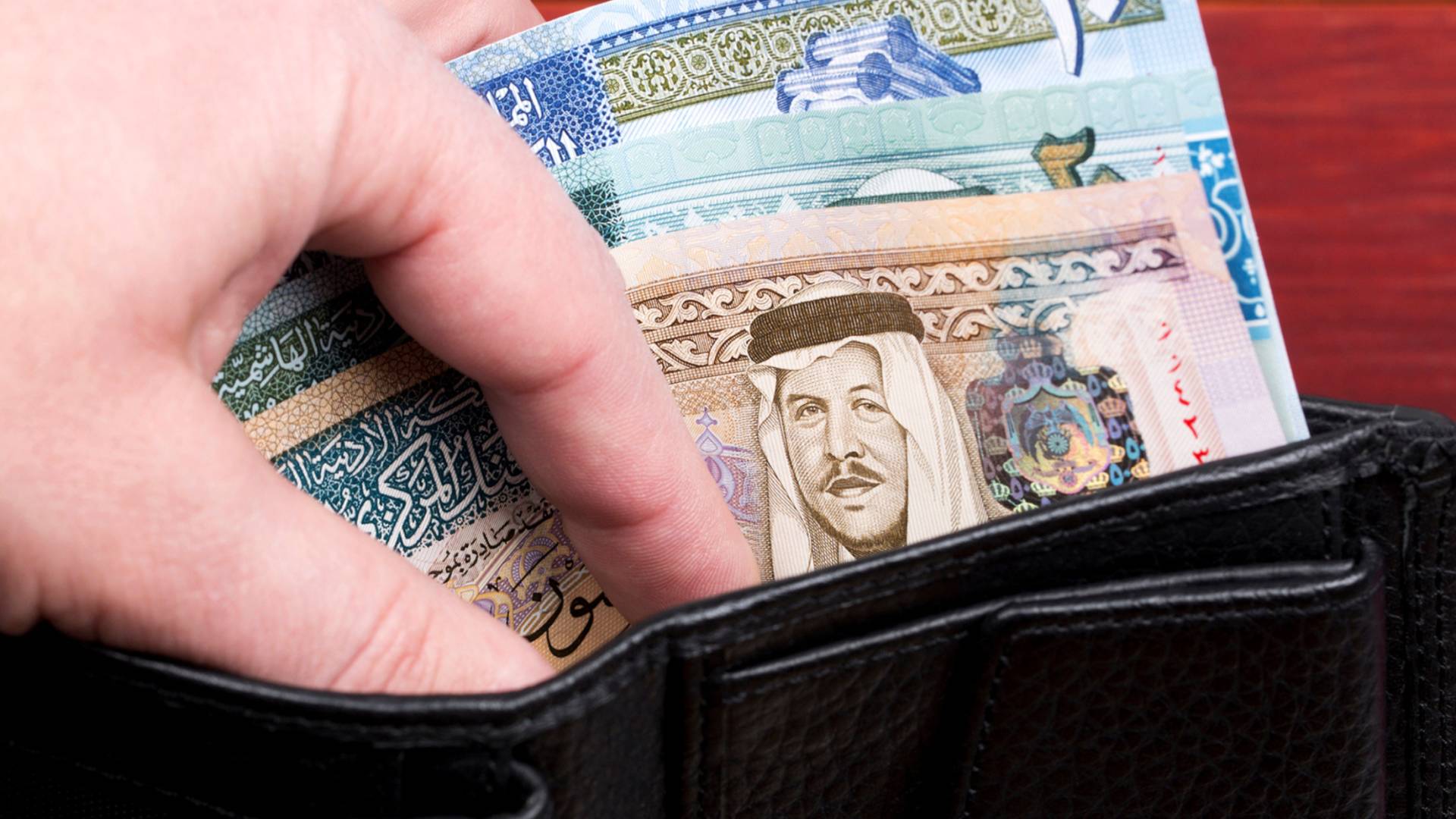 شخص يحمل محفظة بداخلاها مبلغ مالي