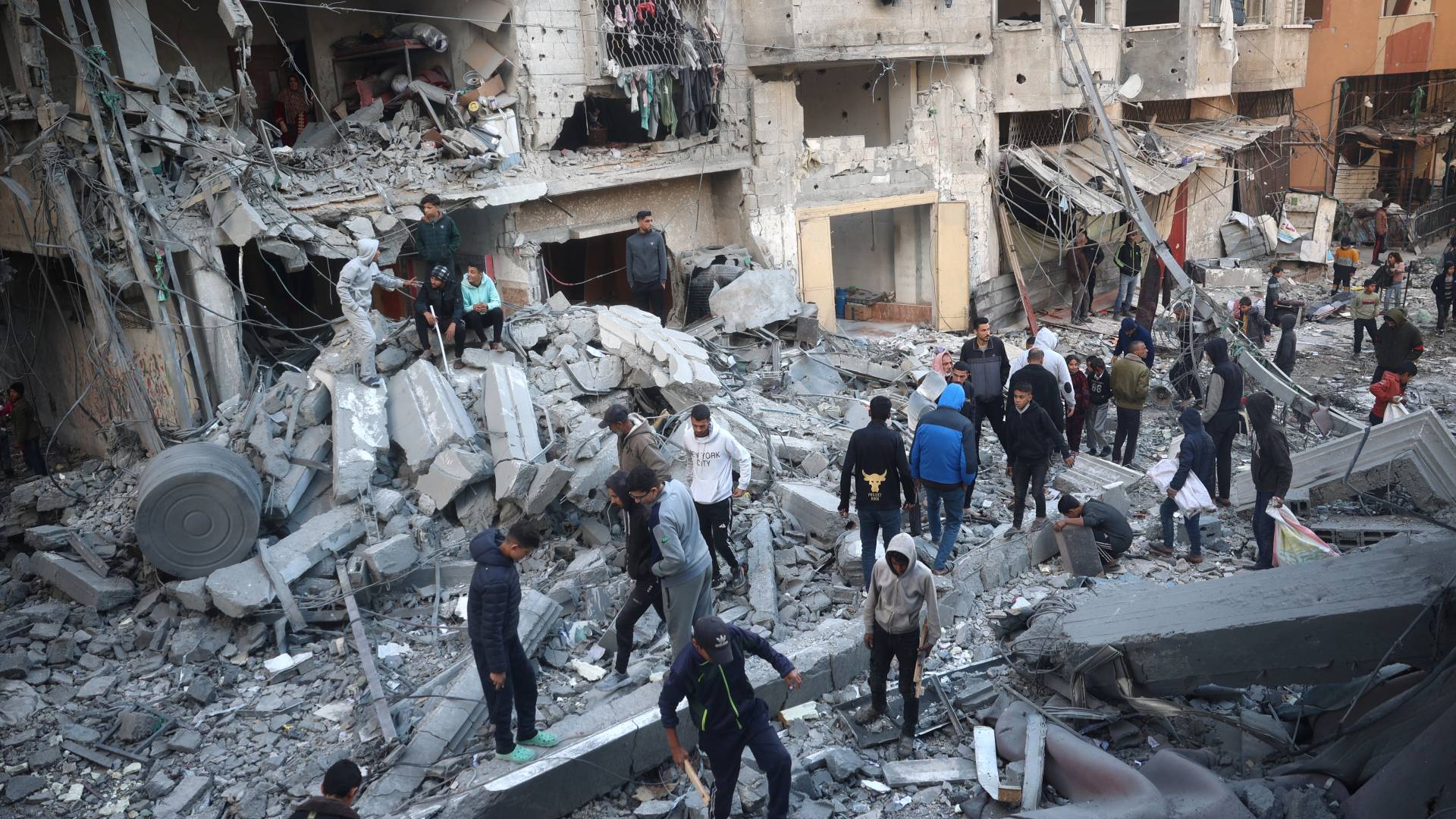 فلسطينيون فوق دمار مبان جراء غارة للاحتلال على مخيم النصيرات وسط غزة