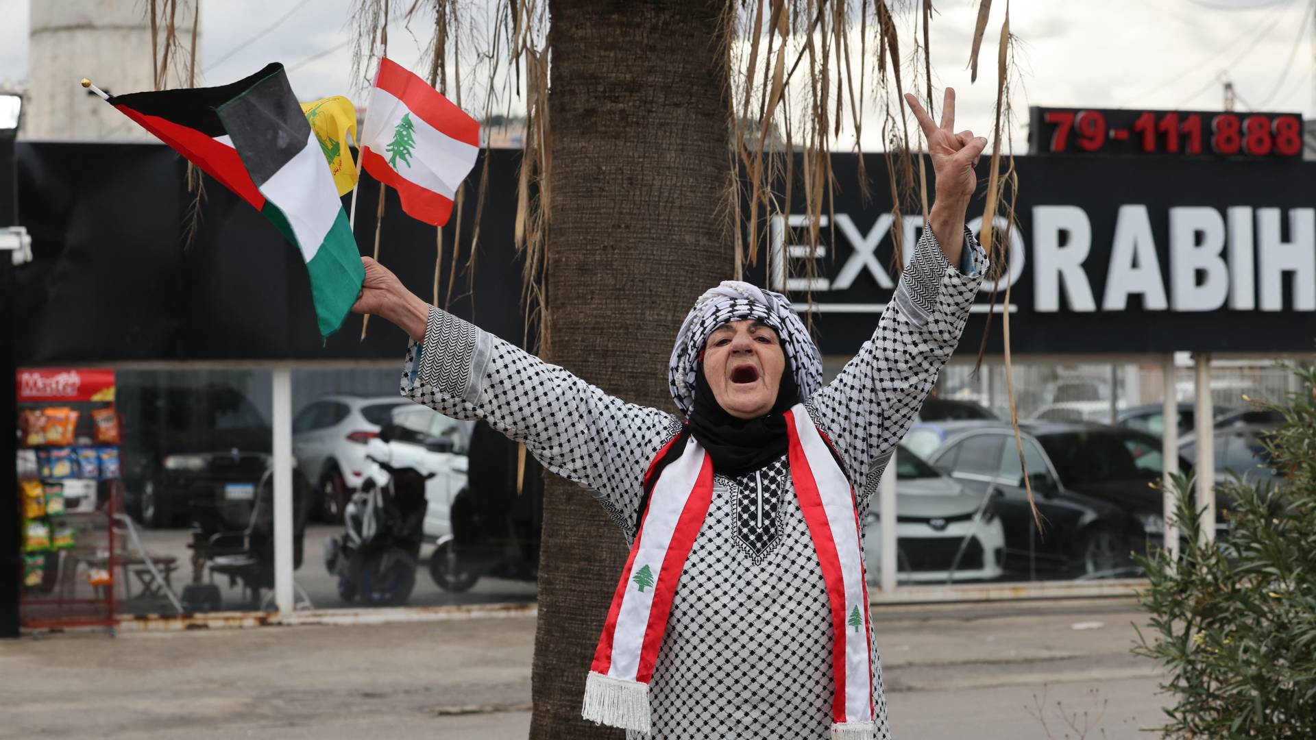 لبنانية ترفع إشارة النصر وأعلام لبنان وفلسطين احتفلا بوقف إطلاق النار
