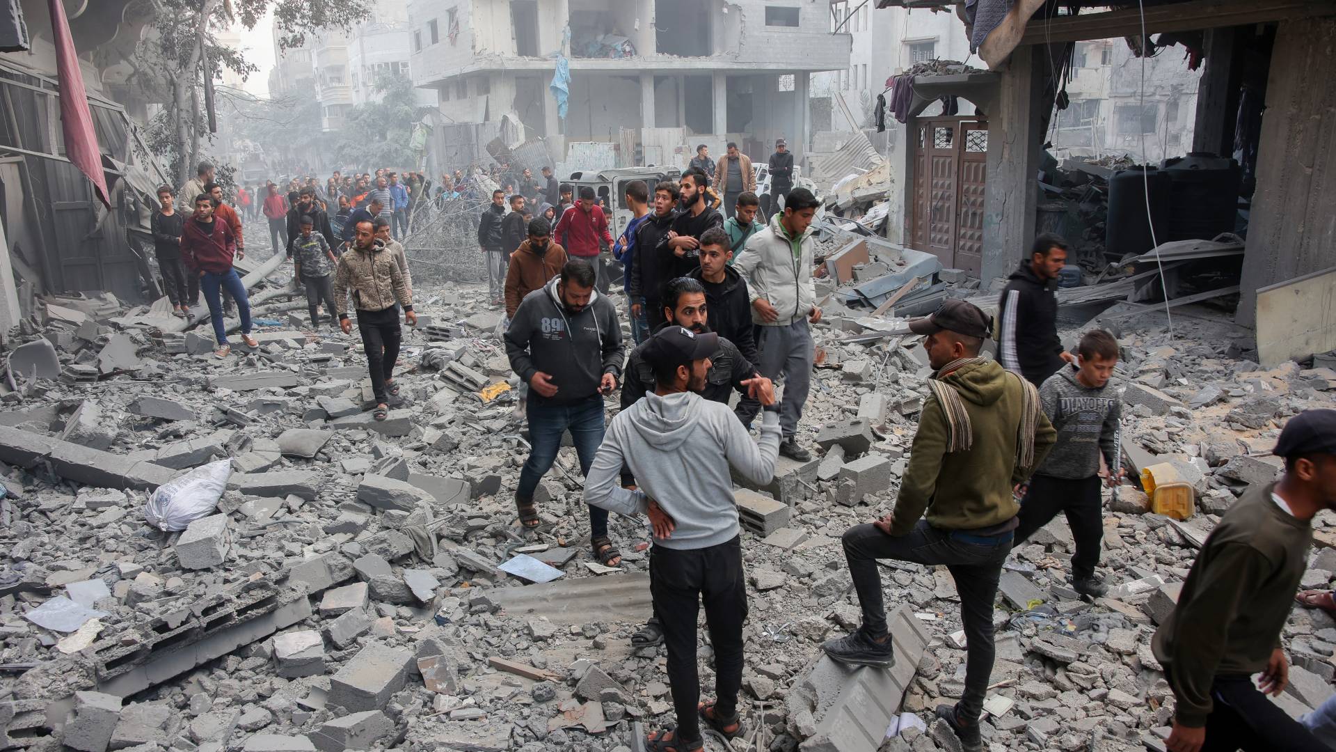 أشخاص يتفقدون موقع غارة للاحتلال في حي الصبرة بمدينة غزة