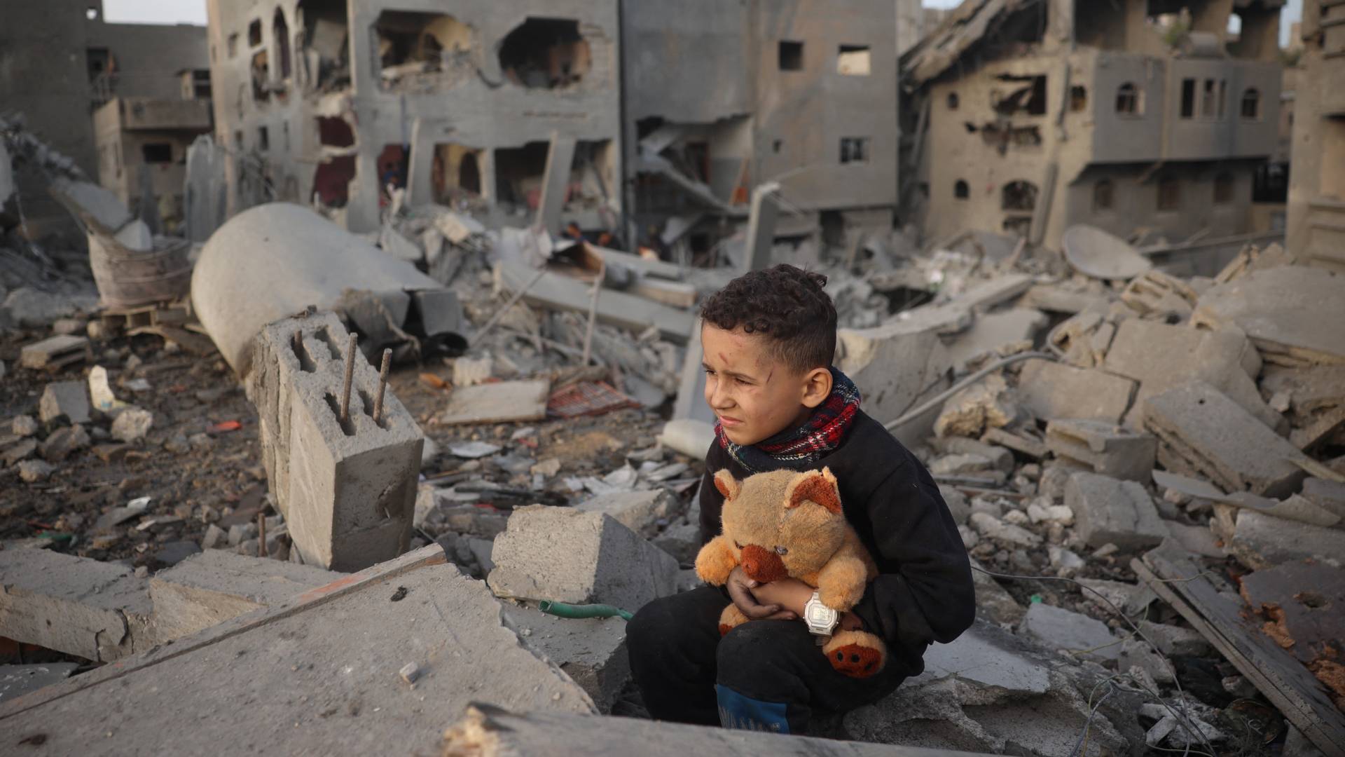 طفل فلسطيني يجلس فوق أنقاض مبنى دمرته غارة للاحتلال في مخيم النصيرات