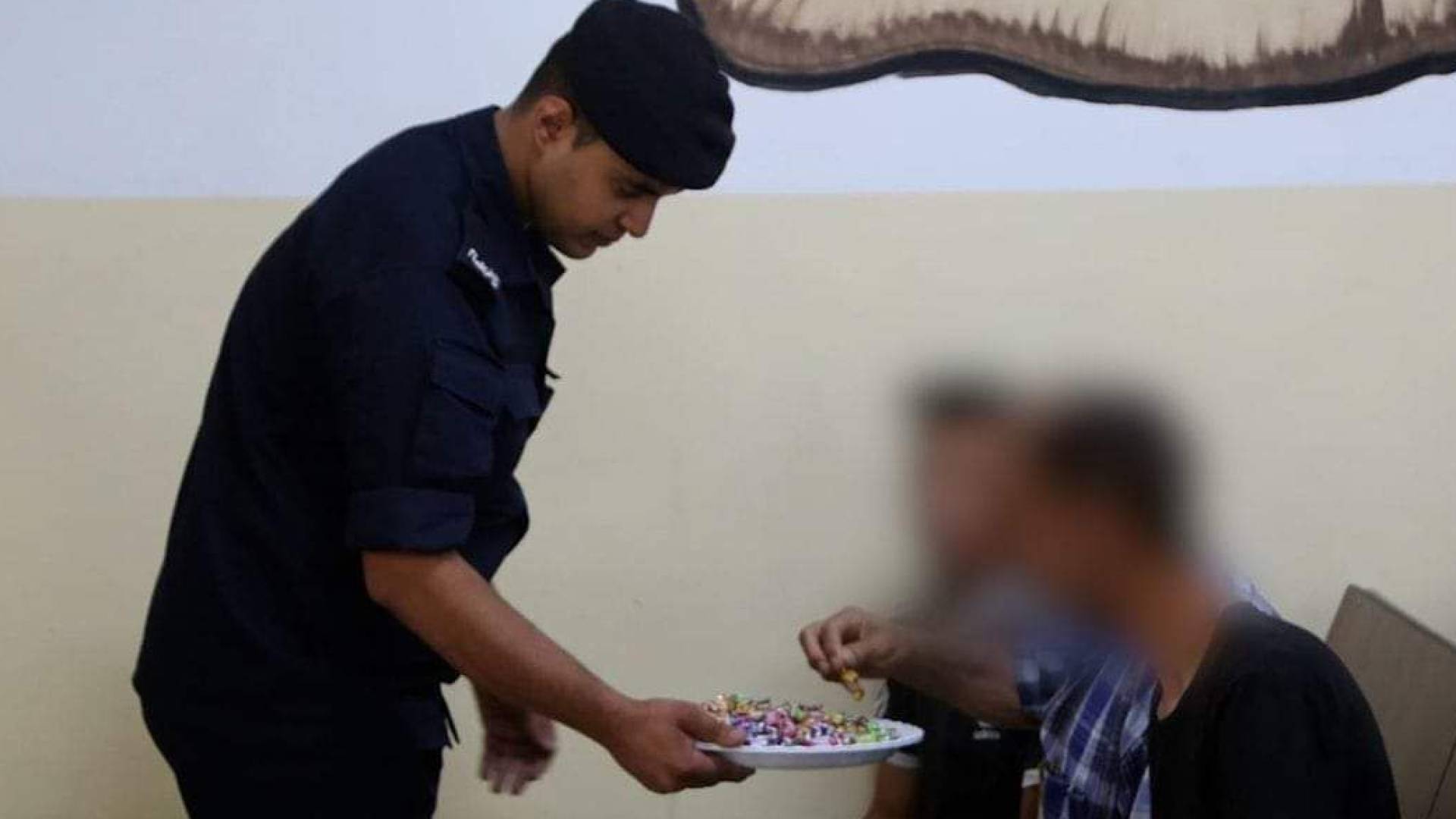 رجل أمن يقدم الحلوى لنزلاء في أحد مراكز الإصلاح في الأردن