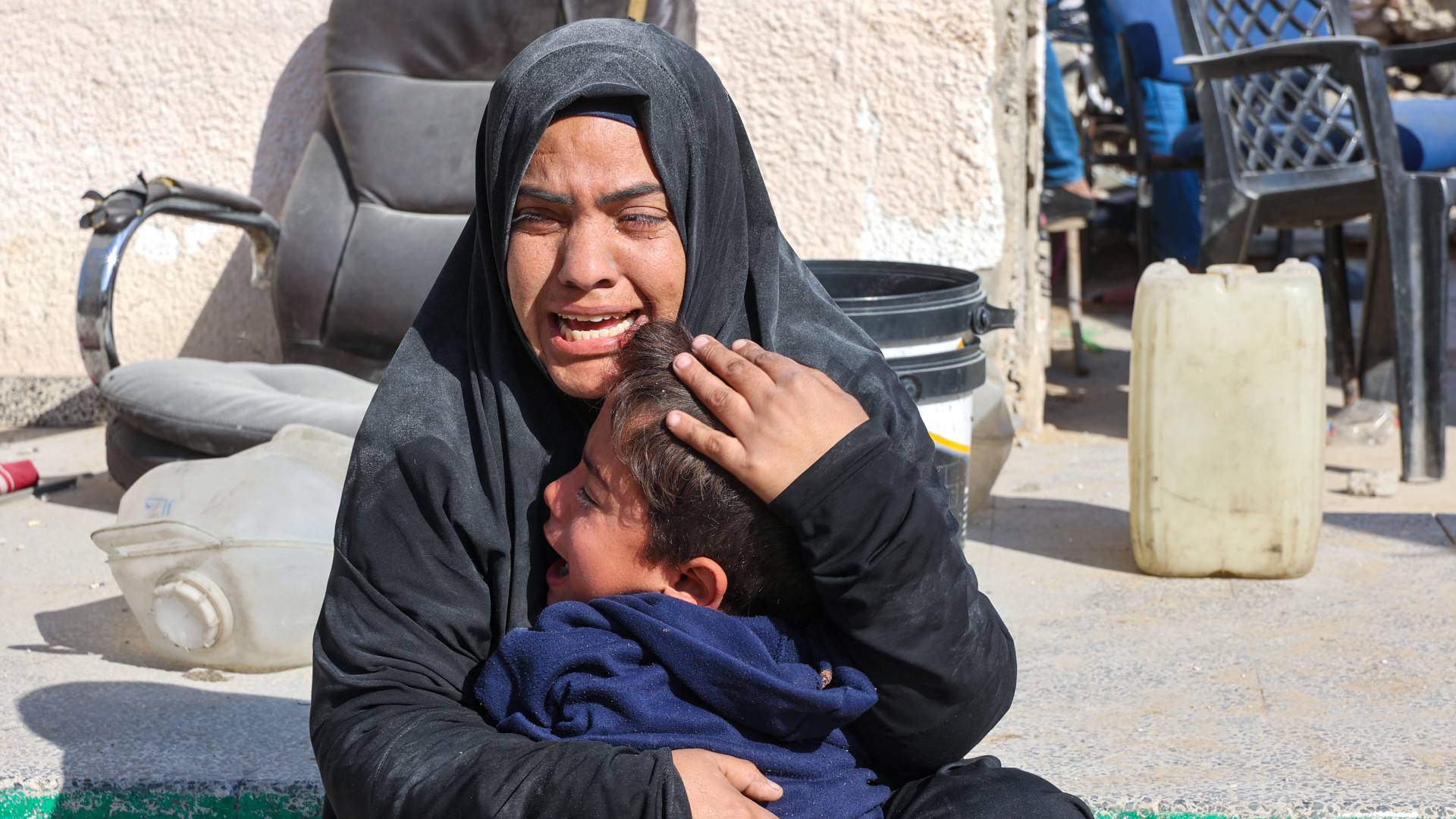 امرأة تبكي مع طفل بعد غارة للاحتلال على مدرسة المجيدة الوسيلة الحكومية التابعة للأونروا