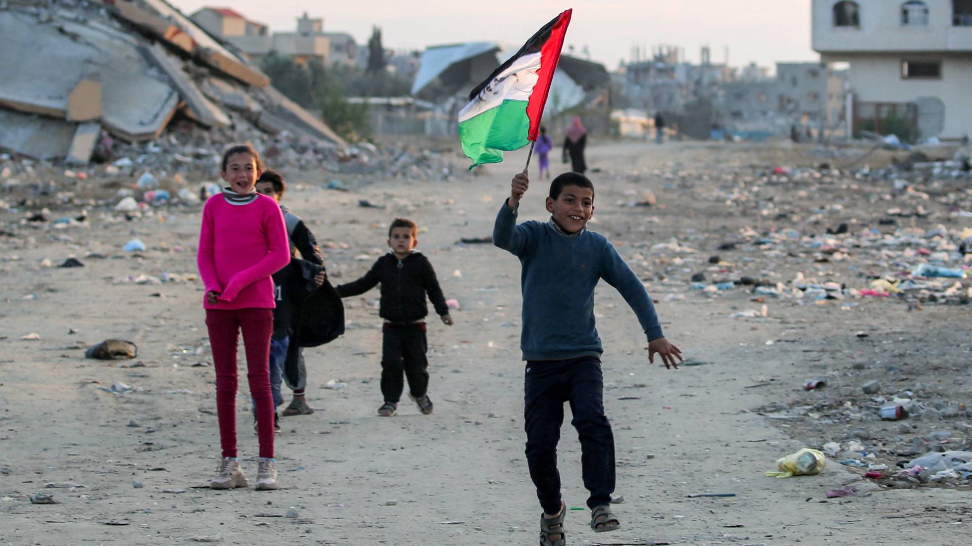 صبي في غزة يركض حاملا علما فلسطينيا مكتوبا عليه "نفدي أنفسنا من أجل الوطن"