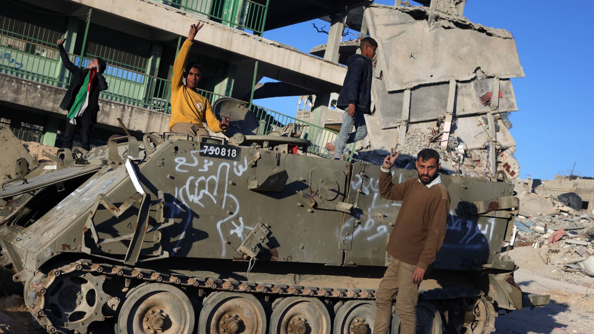 فلسطيني يرفع إشارة النصر بجانب دبابة للاحتلال في غزة