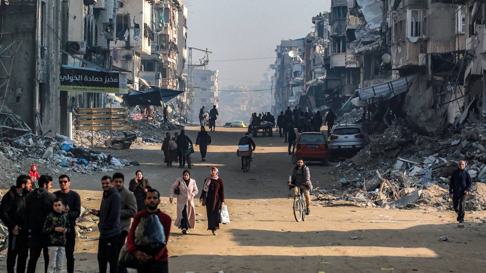 فلسطينيون يسيرون بجانب المباني المدمرة في مدينة غزة