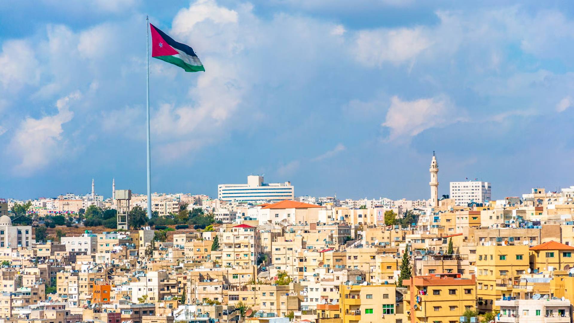 العلم الأردني وجانب من منطقة واد الحدادة في العاصمة عمان