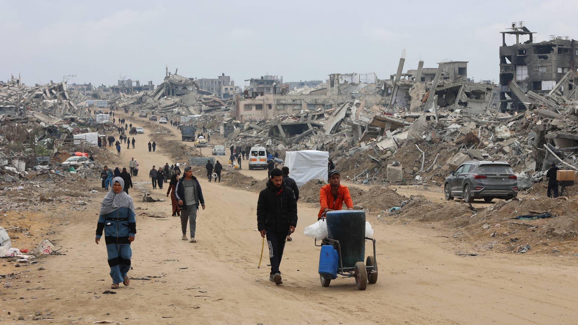 فلسطينيون يسيرون بجوار المباني المنهارة على طول شارع الصفطاوي في جباليا في شمال قطاع غزة