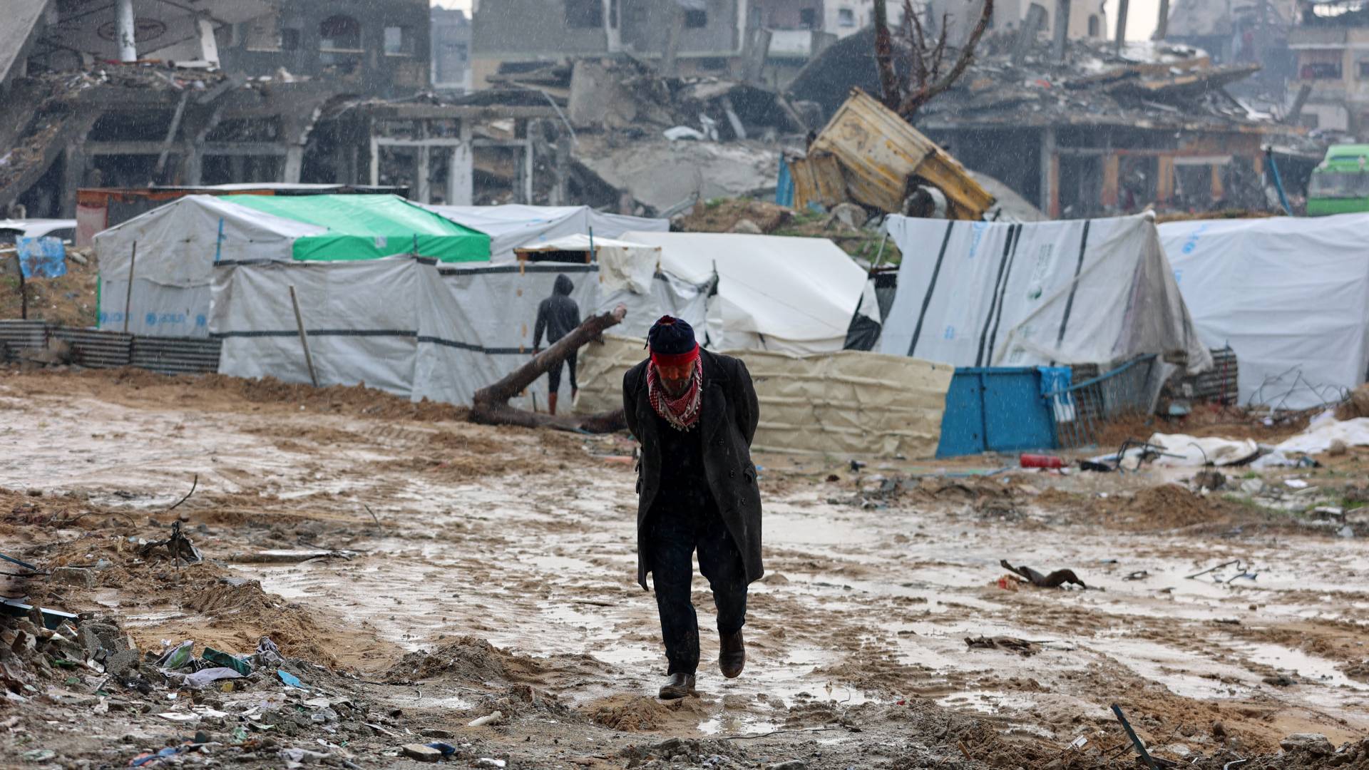 رجل فلسطيني يسير أمام الخيام التي أقيمت وسط الدمار في بيت حانون