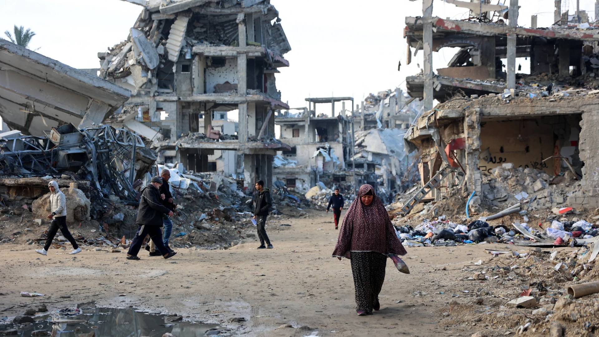 فلسطينيون يسيرون بين الأنقاض بغزة