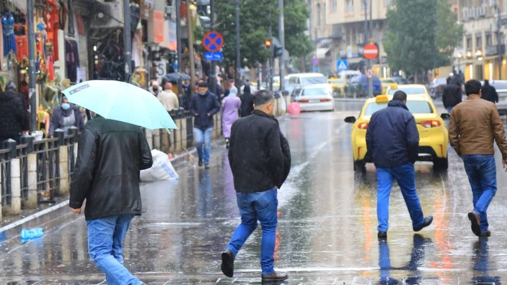 أشخاص يسيرون وسط انهمار المطر