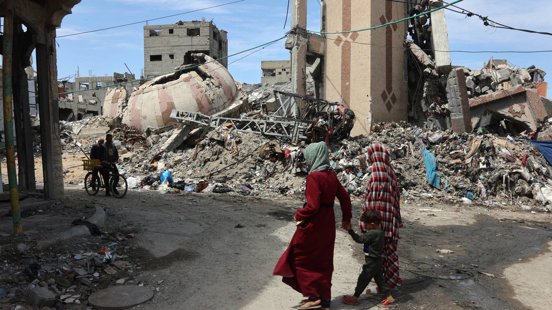 فلسطينيون يسيرون بين أنقاض المباني المدمرة خلال العدوان على غزة