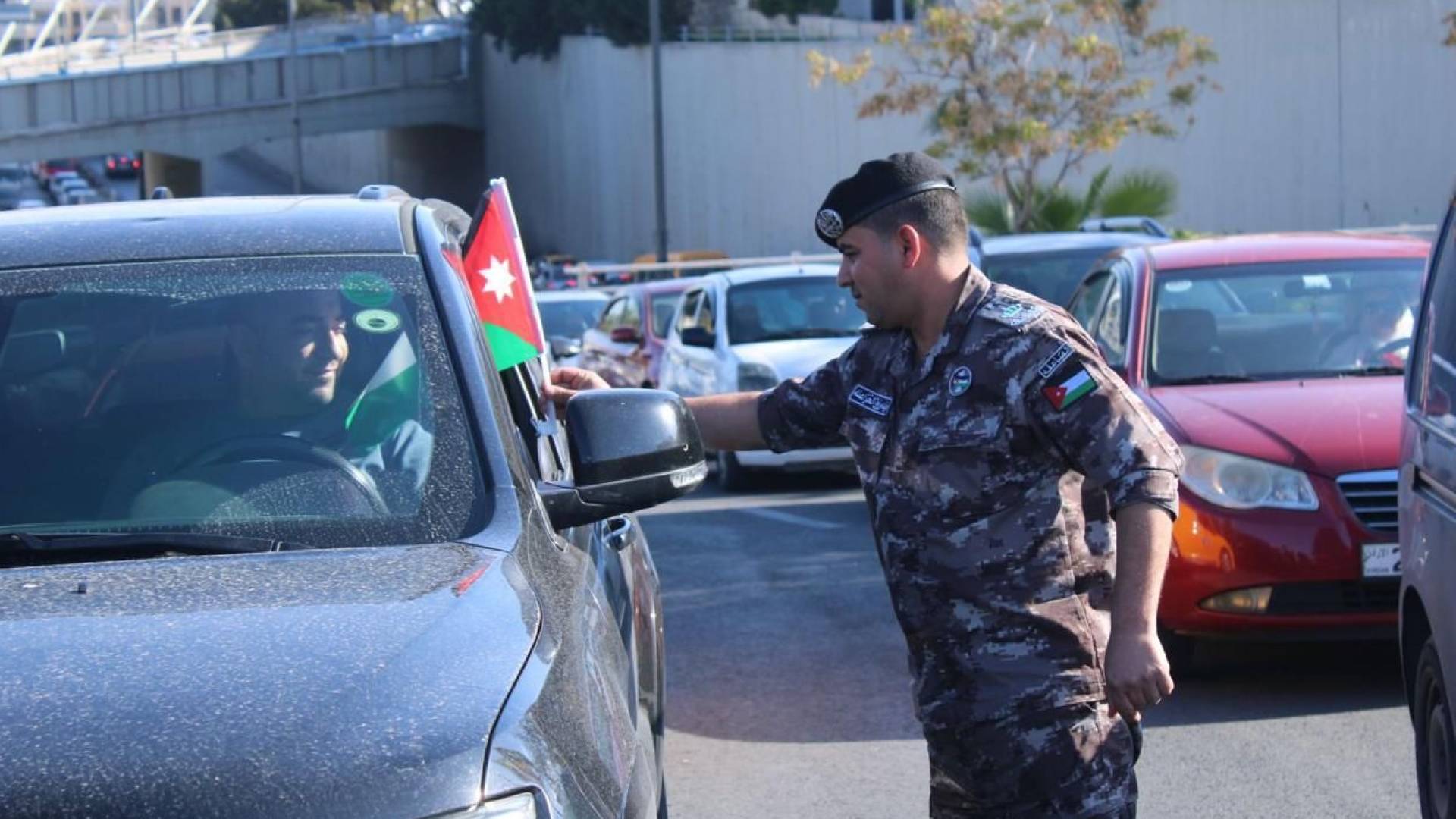 رجل أمن يوزع الأعلام على السائقين