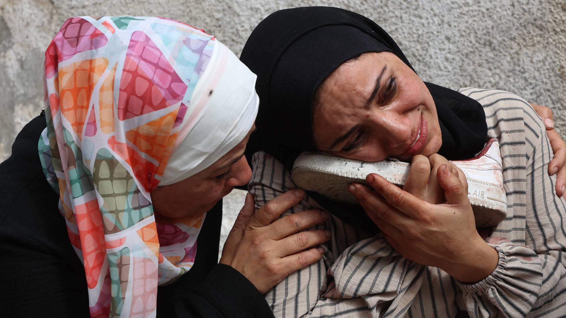 فلسطينية تحتضن حذاء طفلها الشهيد في قطاع غزة