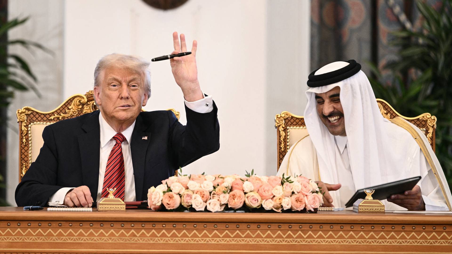 أمير قطر الشيخ تميم بن حمد آل ثاني (يمين) يتفاعل مع رفع الرئيس الأمريكي دونالد ترامب قلمه خلال حفل توقيع في القصر الملكي بالدوحة