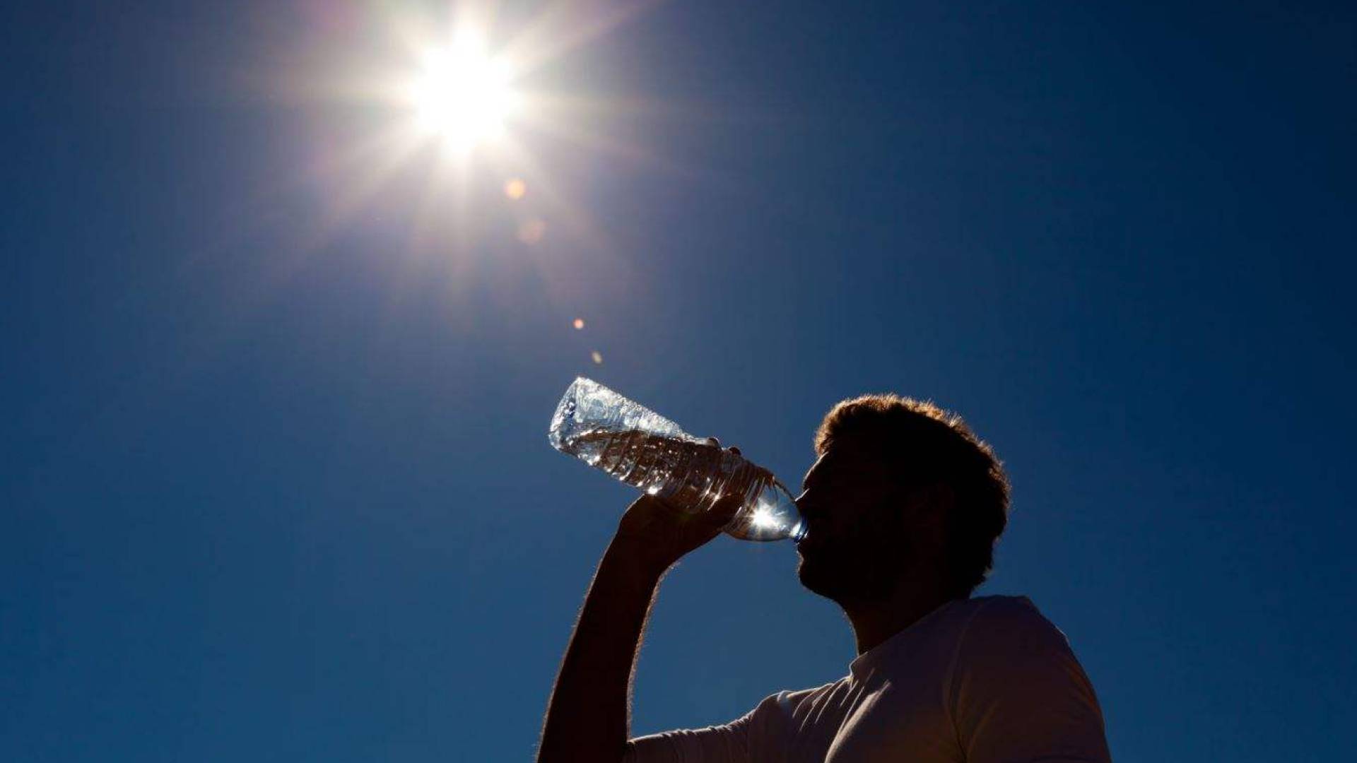 شخص يشرب الماء بسبب الحرارة المرتفعة