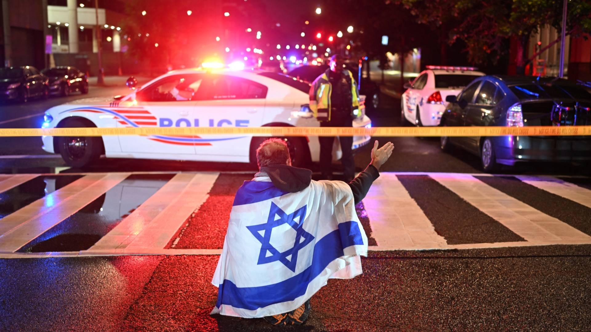 رجل يحمل علم الاحتلال أمام مركبات الشرطة قرب المتحف اليهودي في واشنطن