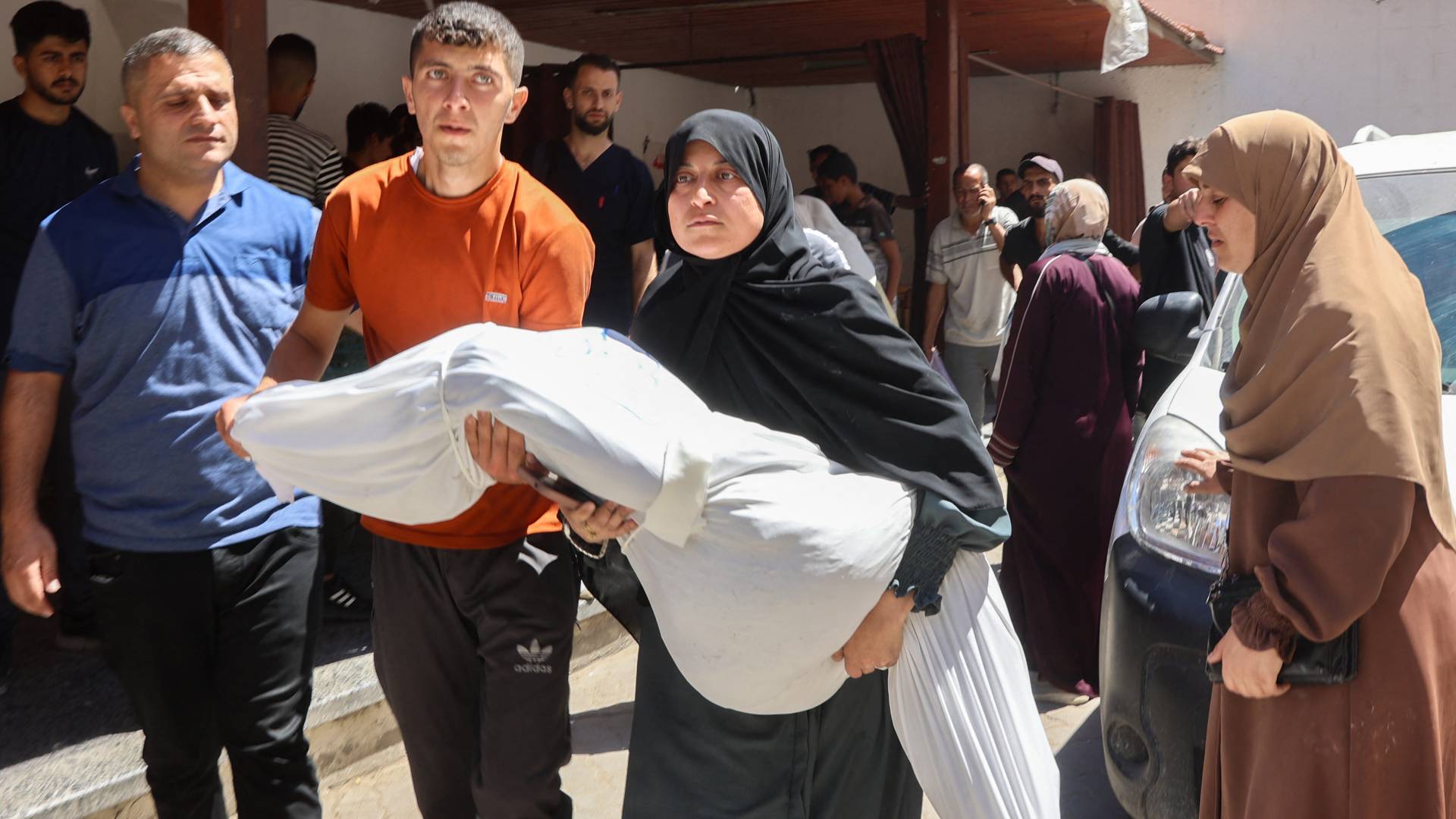 فلسطينية تحمل جثمان ابنها الشهيد في غزة