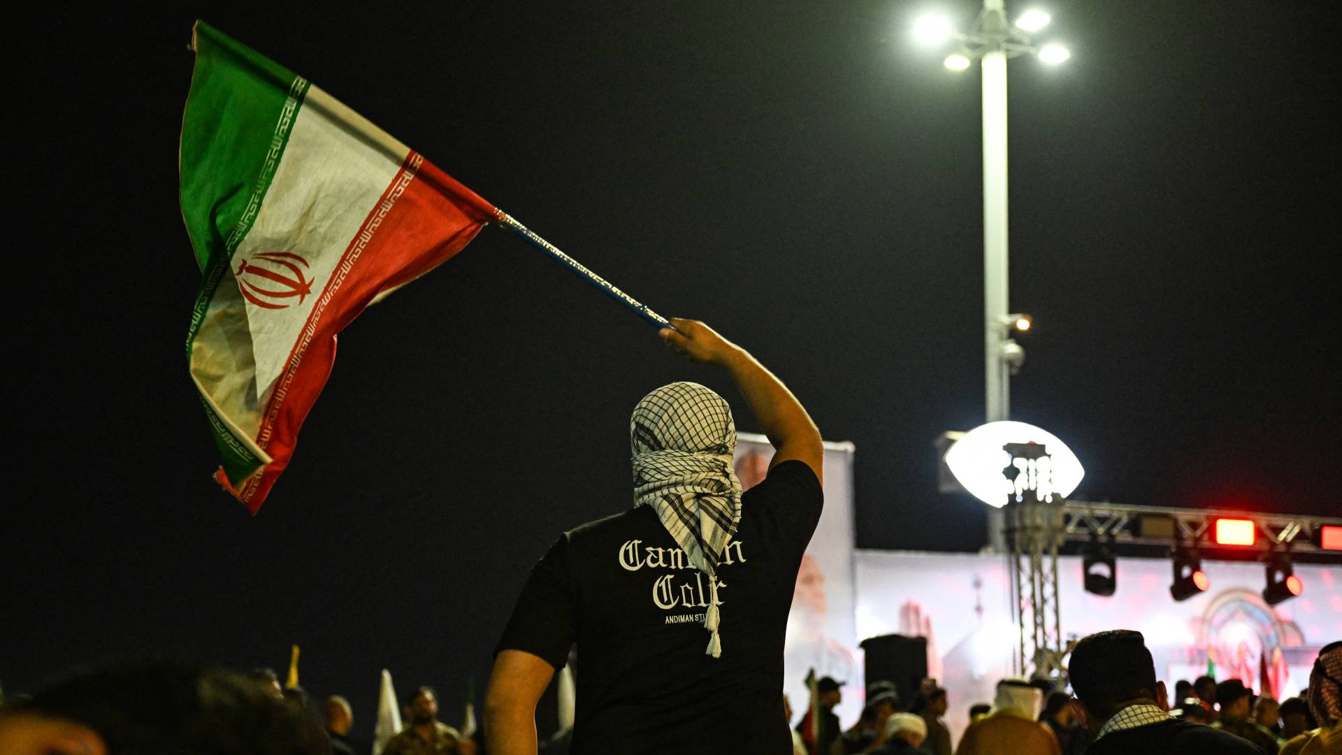 إيراني يرفع علم بلاده بعد الضربات الإيرانية على تل أبيب