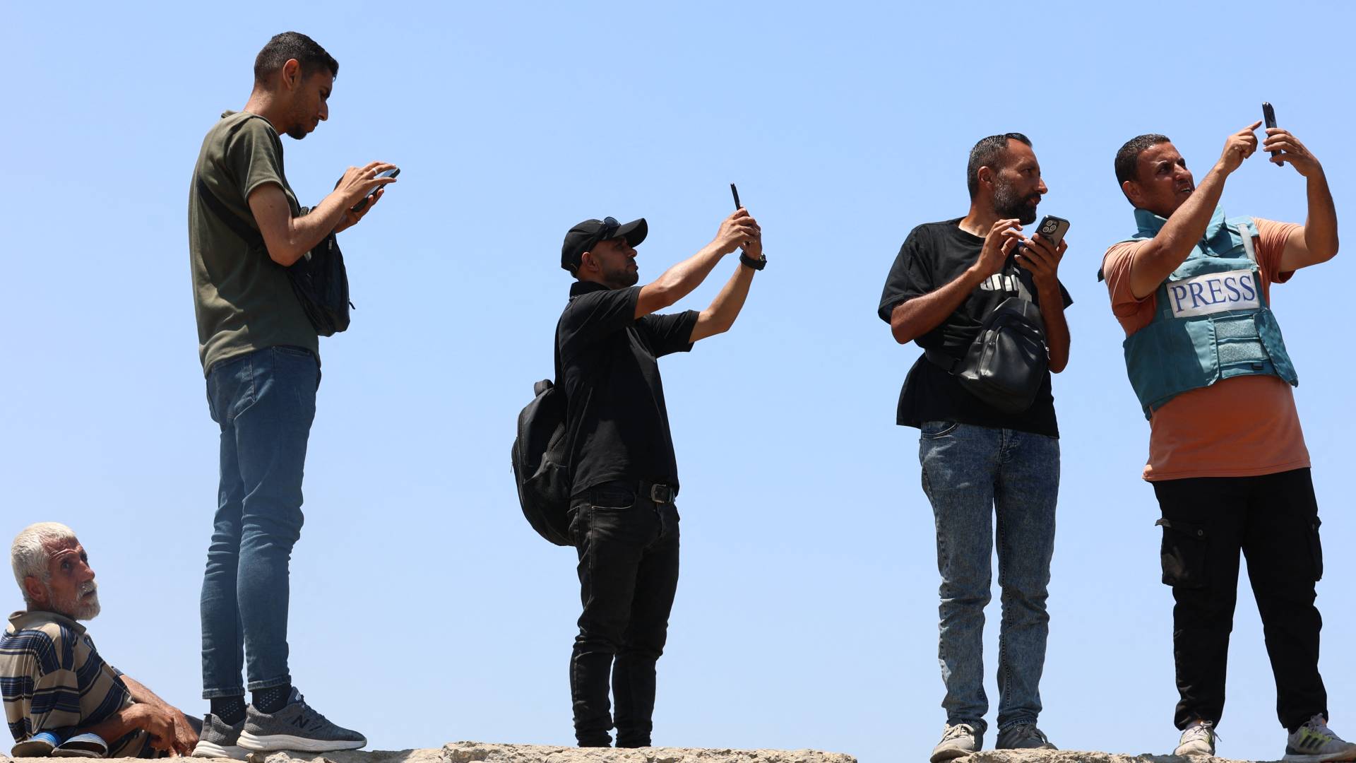 فلسطينيون يرفعون هواتفهم في ميناء مدينة غزة في محاولة لالتقاط إشارة إنترنت