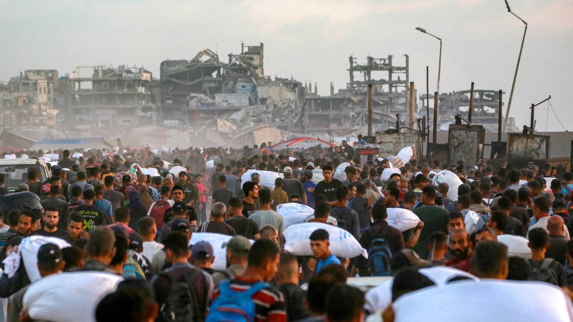 أشخاص يحملون دقيقا في شارع الرشيد بغزة