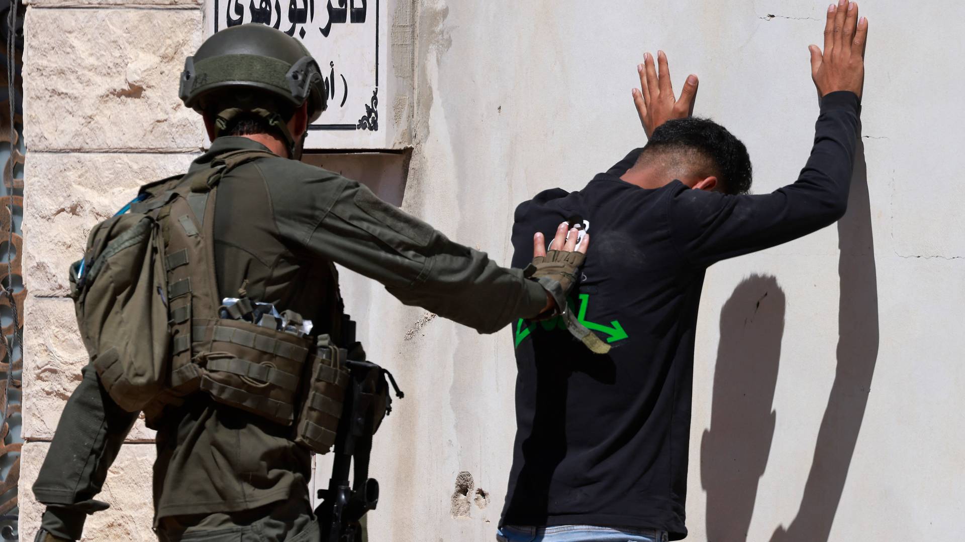 جندي من جيش الاحتلال يفتش شابا فلسطينيا في الضفة الغربية