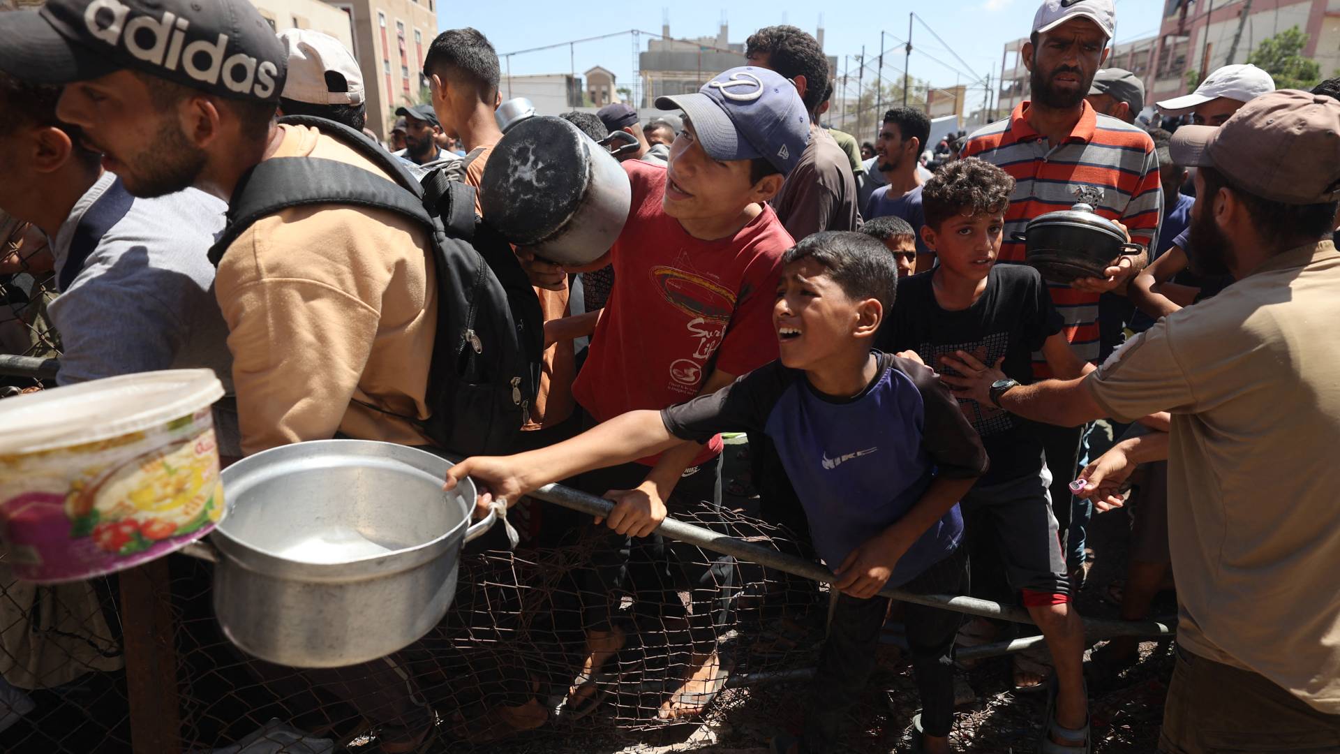 يتجمع فلسطينيون عند نقطة توزيع غذاء في مخيم النصيرات للاجئين وسط قطاع غزة،