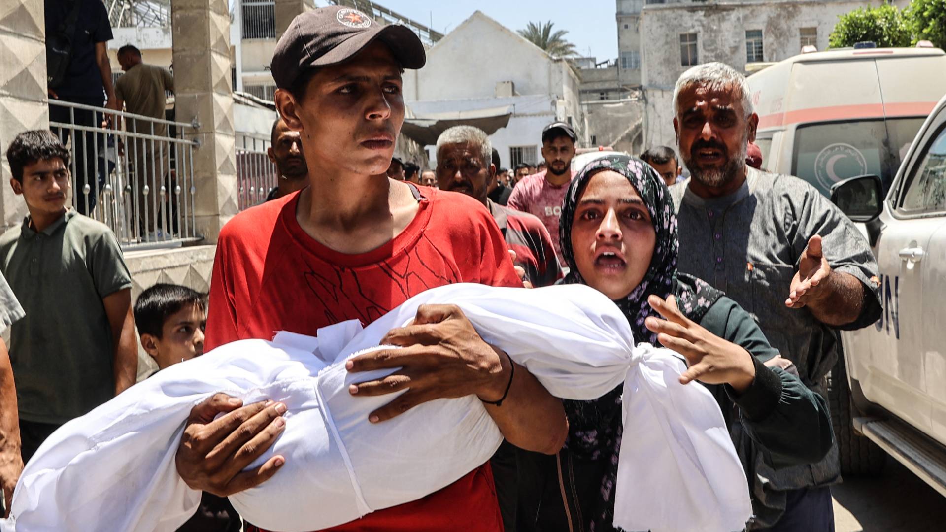 فلسطيني يحمل ابنه الشهيد في غزة