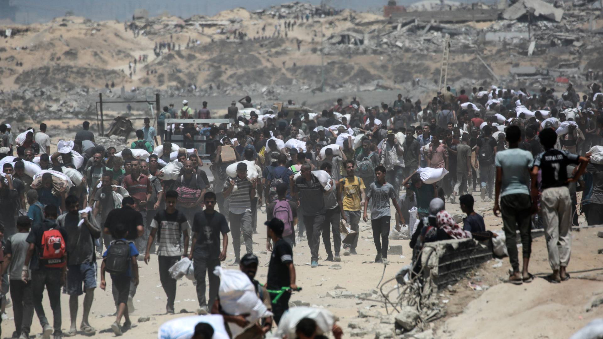 فلسطينيون يحملون أكياس الطحين في غزة