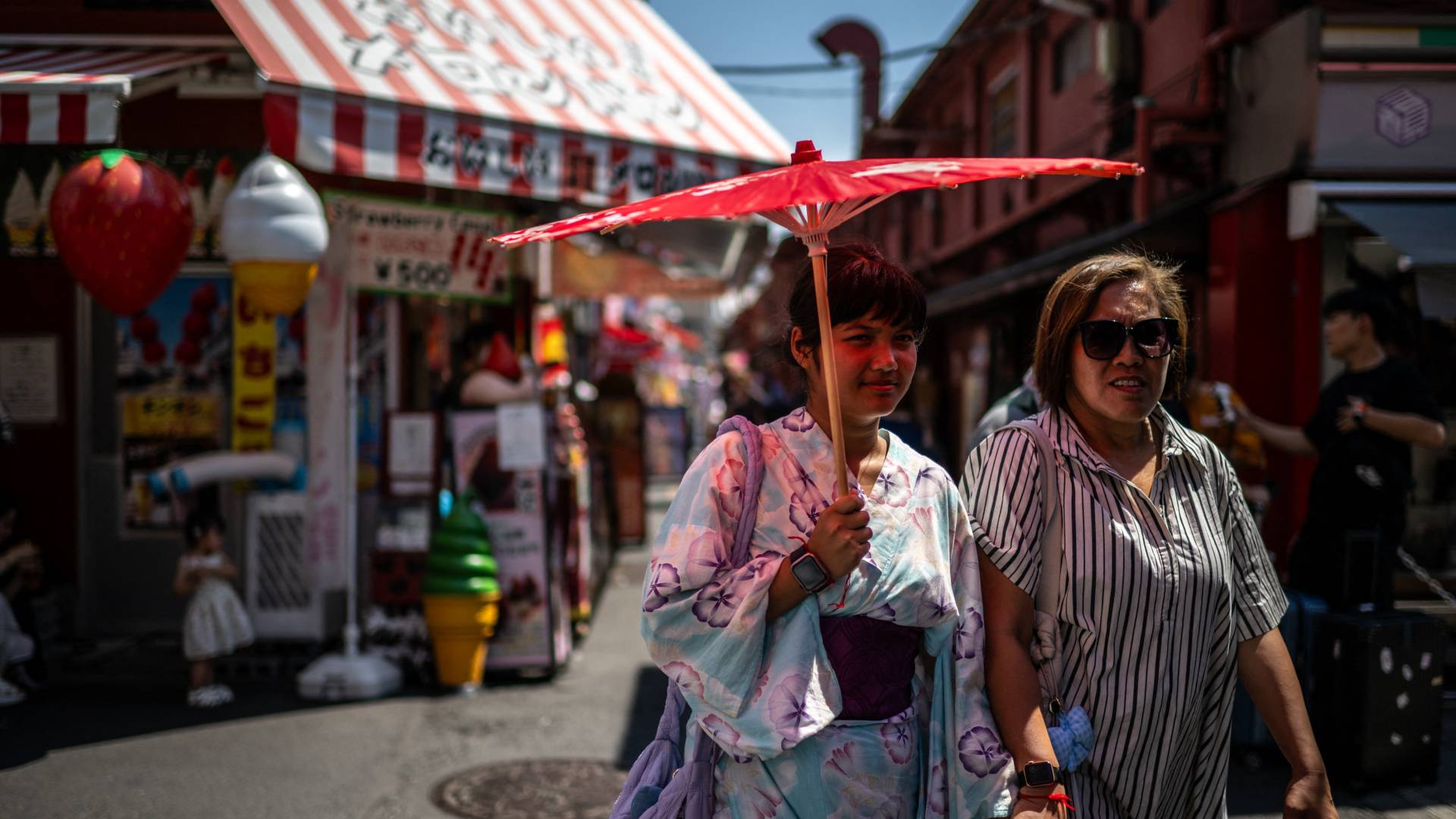 اليابان-مواطنون يحملون مظلة للاحتماء من الشمس