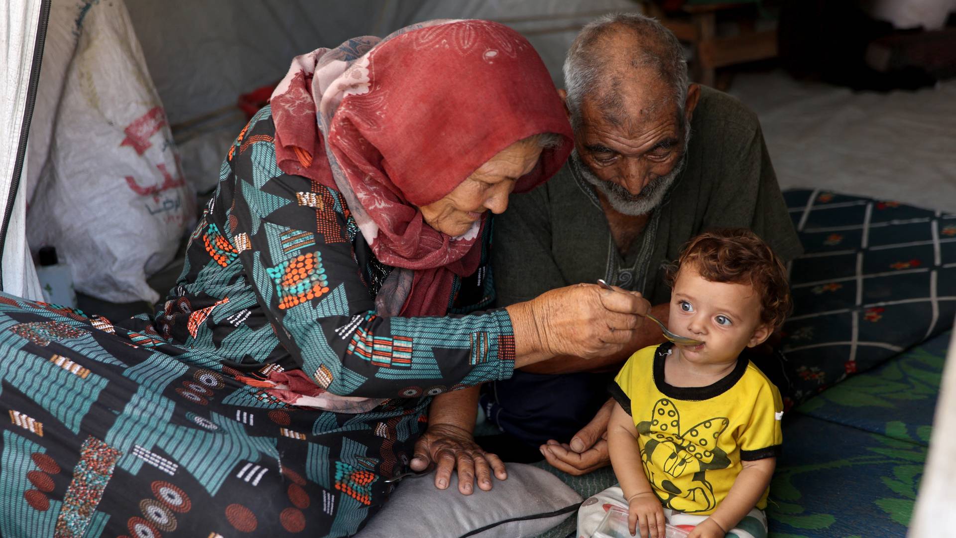 فلسطيني وفلسطينية يقدمان الطعام لحفيدتهما في غزة "أ ف ب"