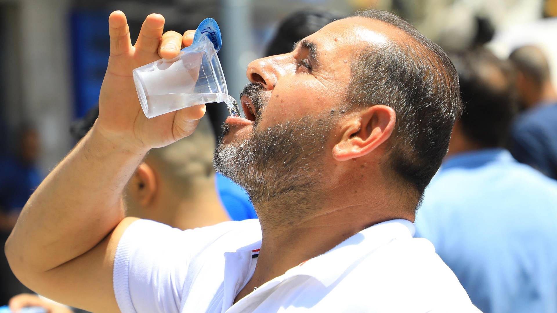 شخص يشرب الماء تحت أشعة الشمس