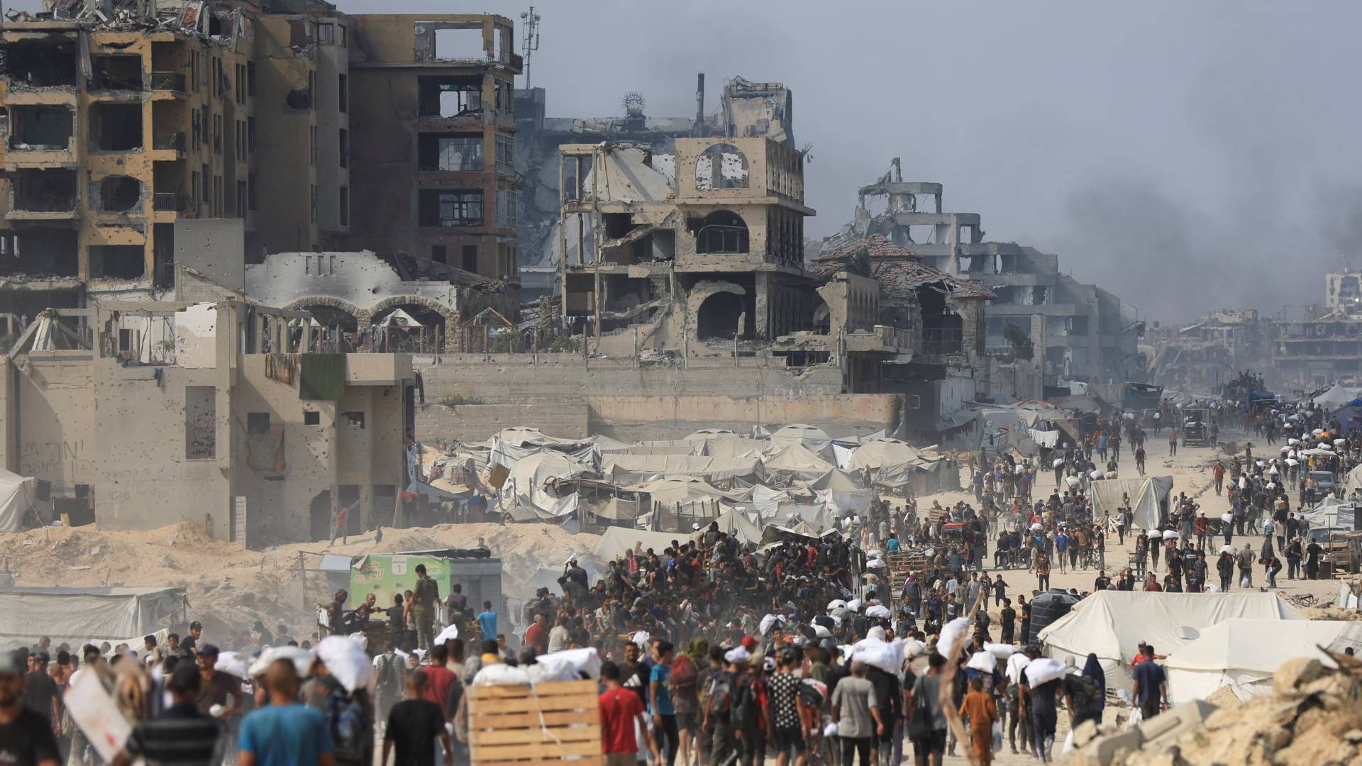 فلسطينيون يسيرون بين الدمار بغزة