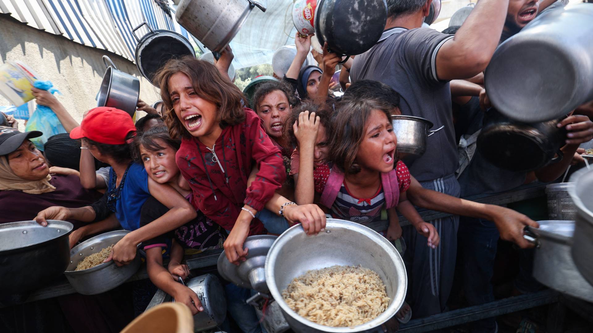 فلسطينيون في نقطة توزيع مساعدات غذائية في مخيم النصيرات في قطاع غزة