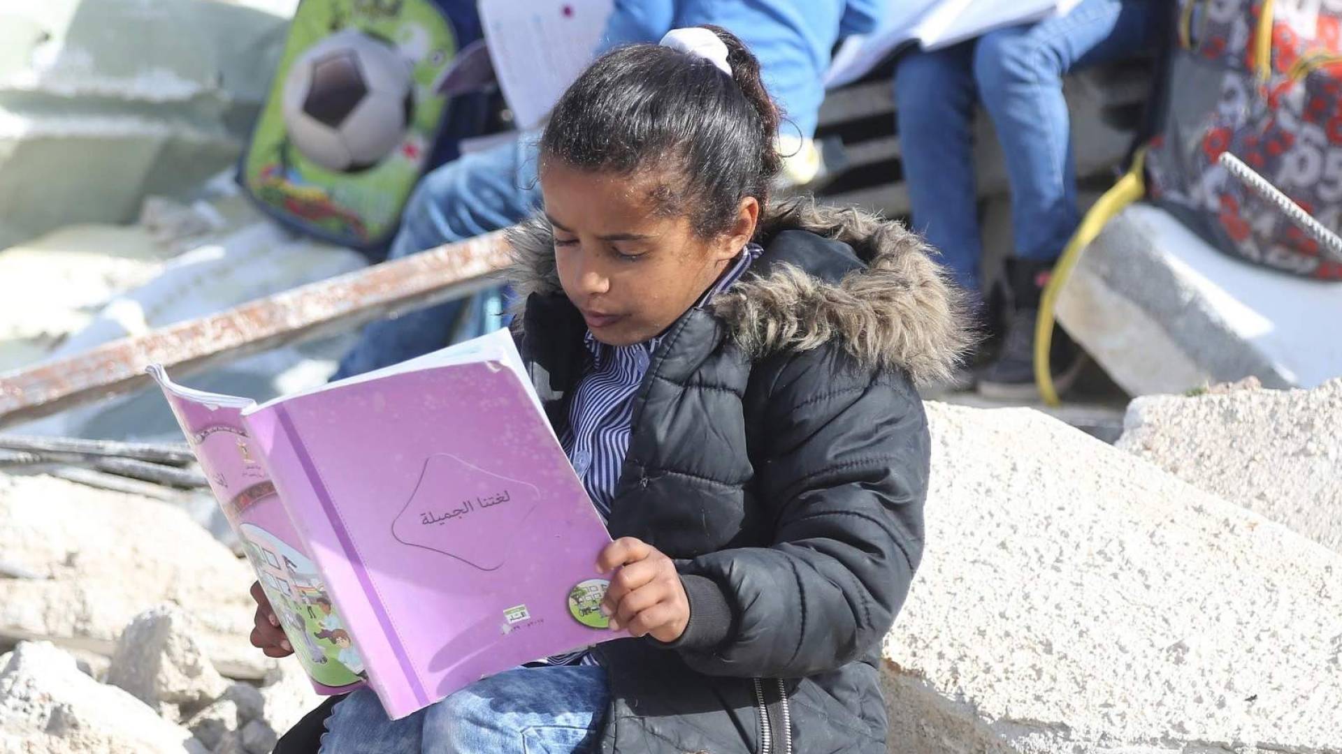طفلة تدرس وحولها اثار الحرب