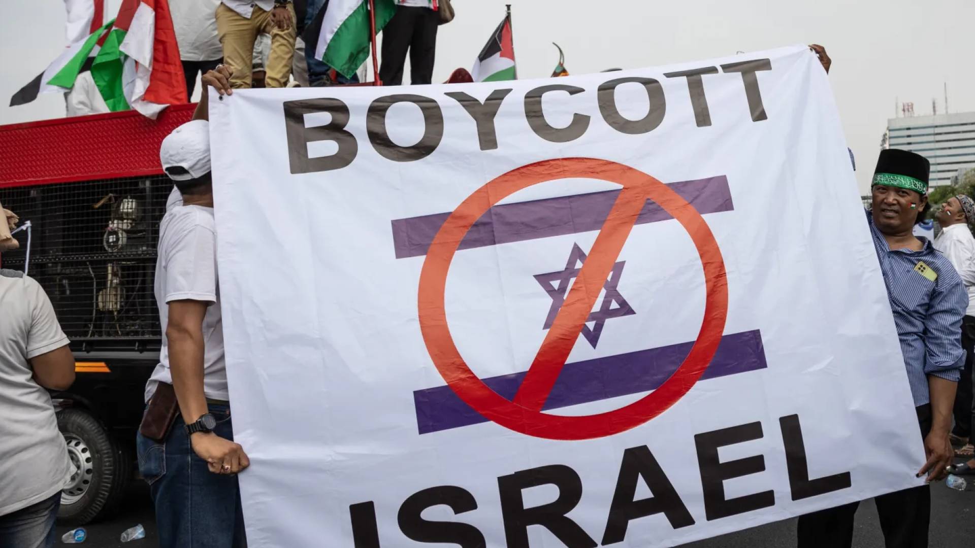 متظاهر يرفع لوحة لمقاطعة كيان الاحتلال