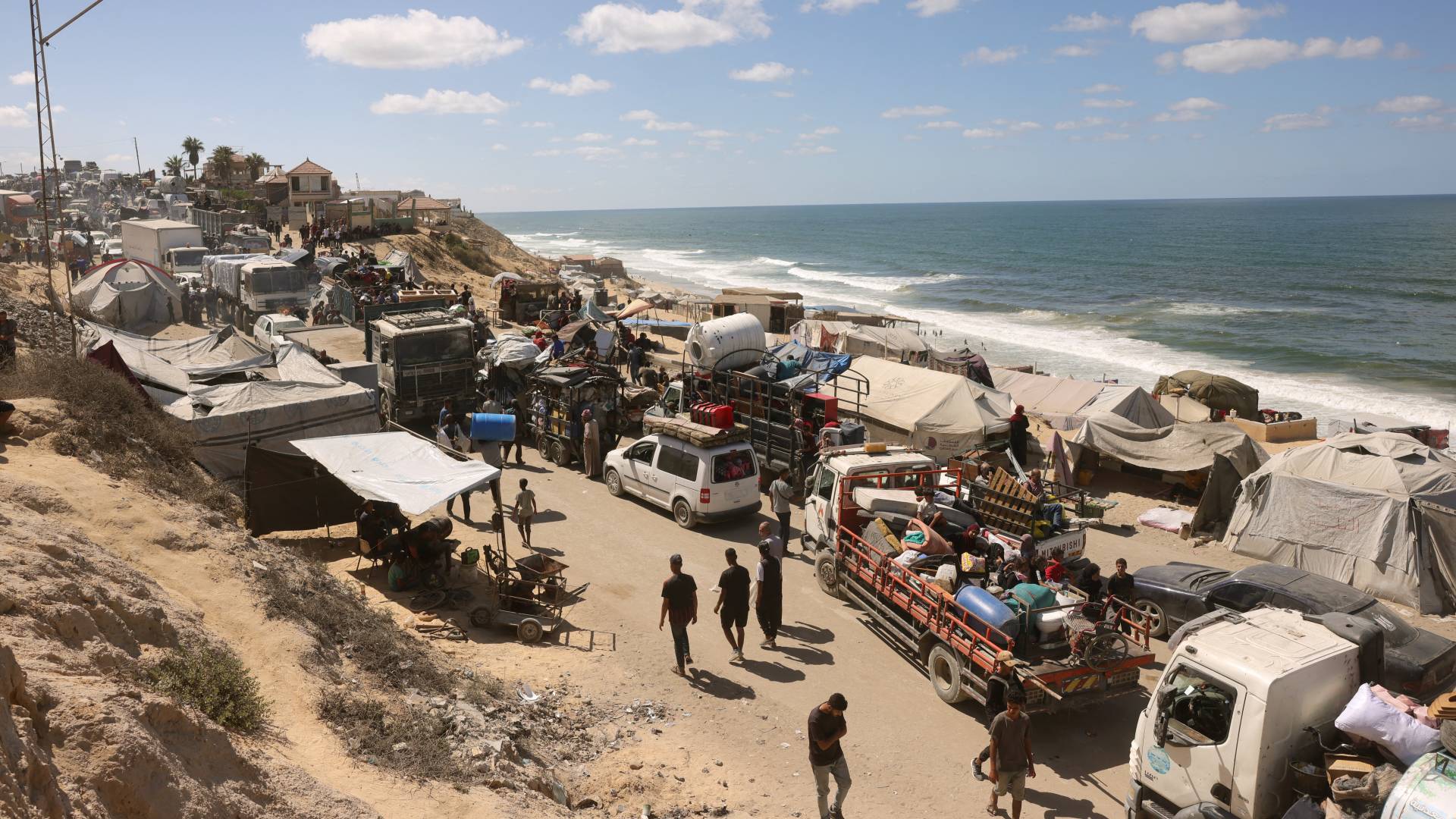 فلسطينيون يحملون متاعهم يسيرون على طريق ساحلي شمال غربي مخيم النصيرات بعد نزوحهم جنوبا