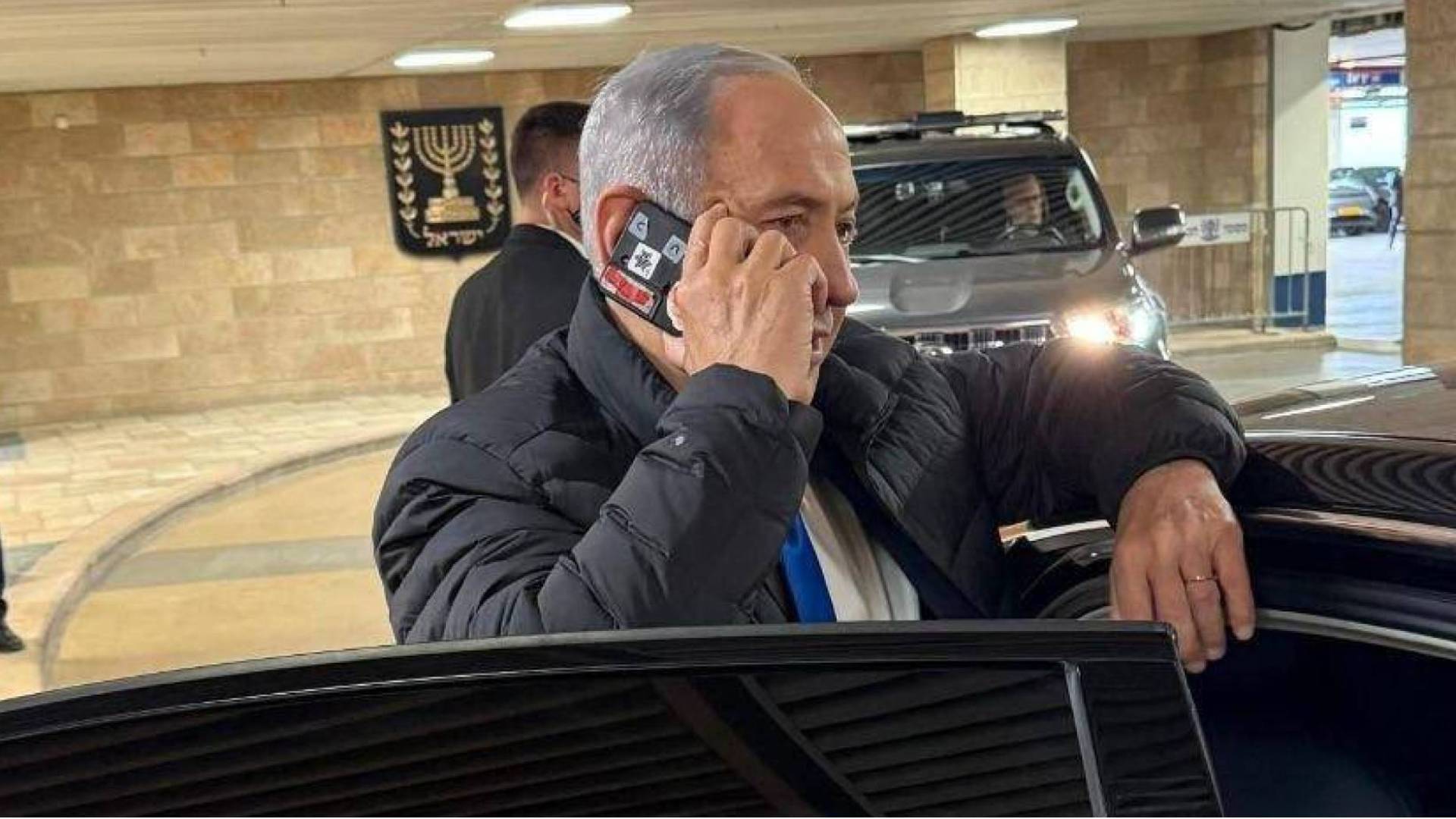 نتنياهو يمسك بهاتف ذكي تم تغطية عدسات كاميرته ومستشعراته بشريط لاصق سميك.