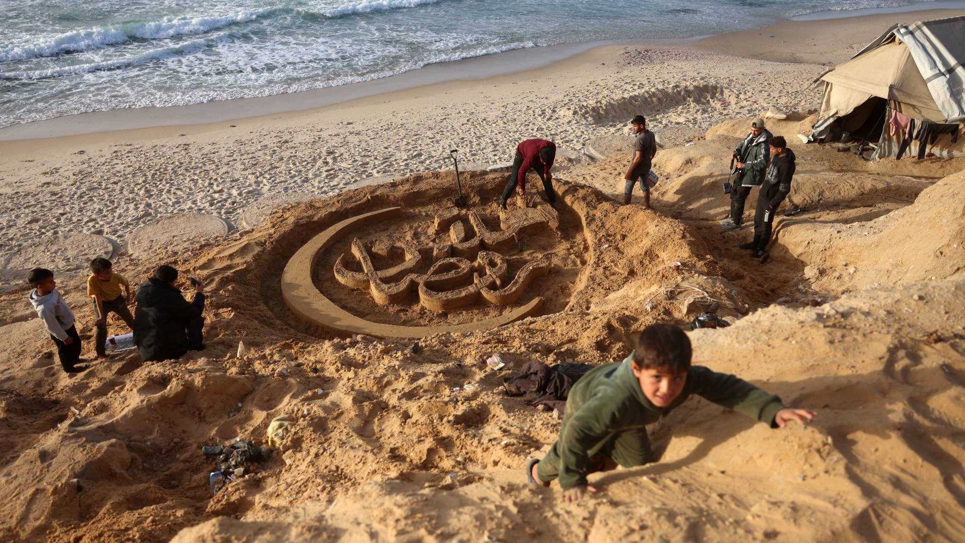منحوتة رملية تحمل عبارة "أهلا رمضان" على شواطئ غزة