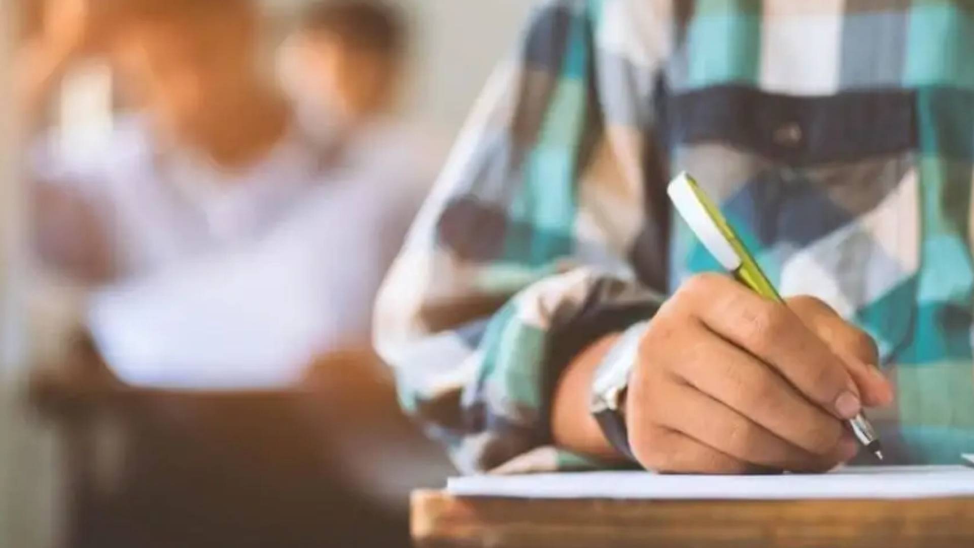 طالب يمسك قلم لحل ورقة الاختبار