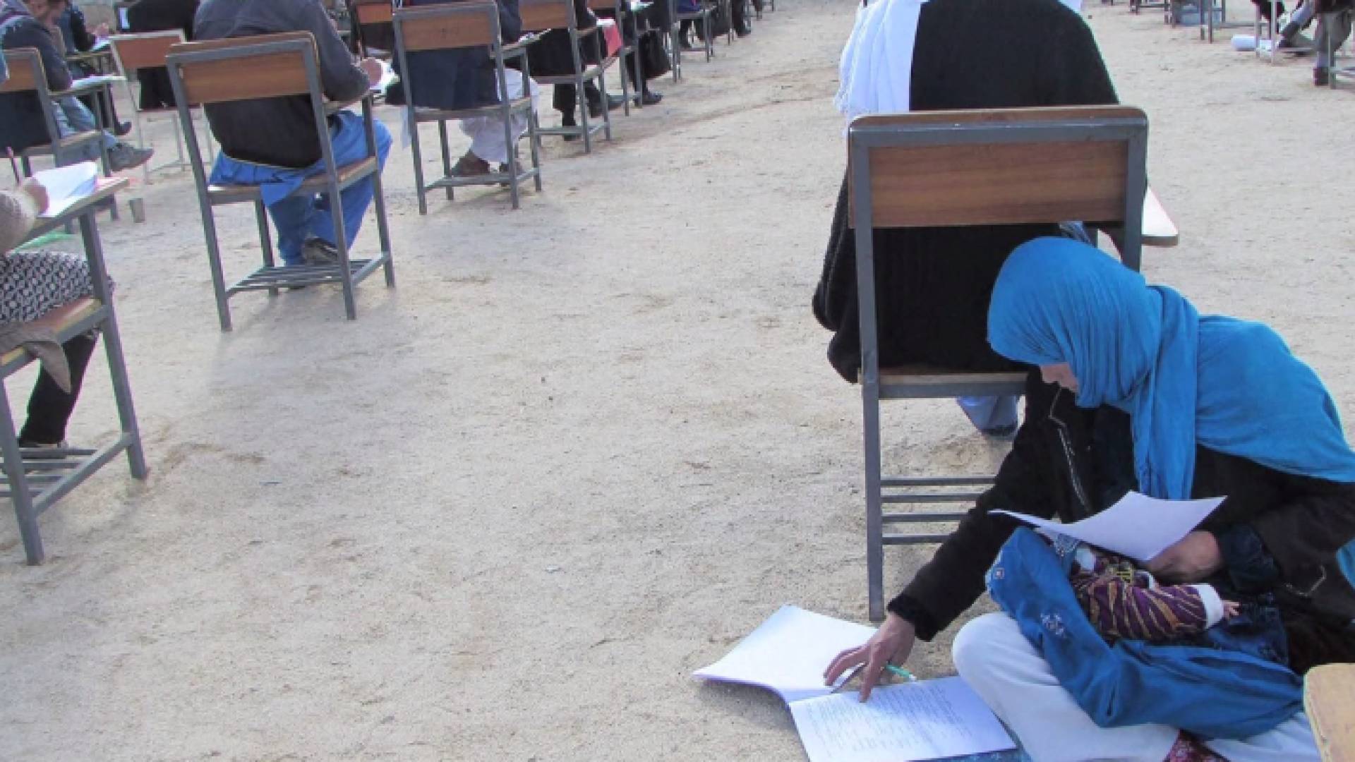 افغانية تفترش الأرض وتعتني بطفلها أثناء الدراسة