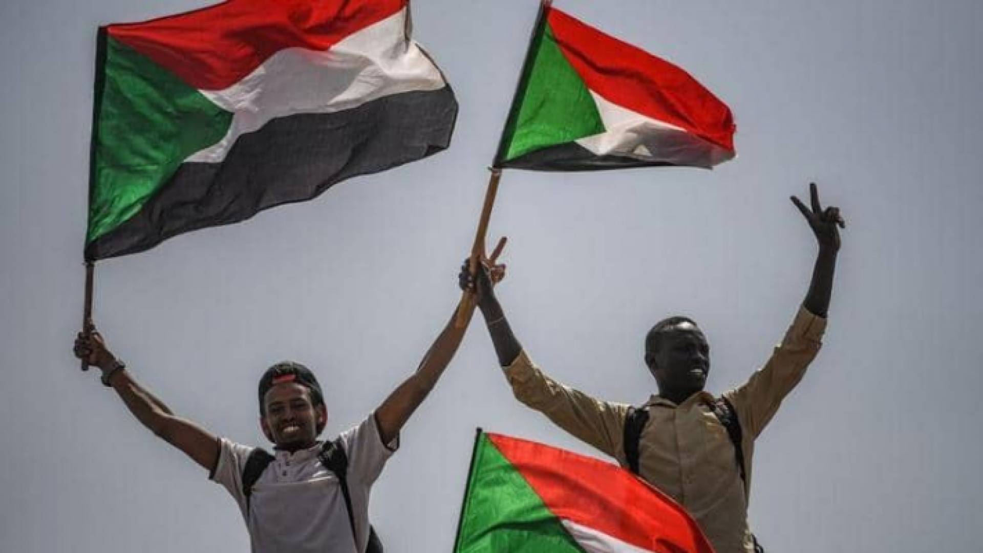 سودانيان يرفعان أعلام بلدهما