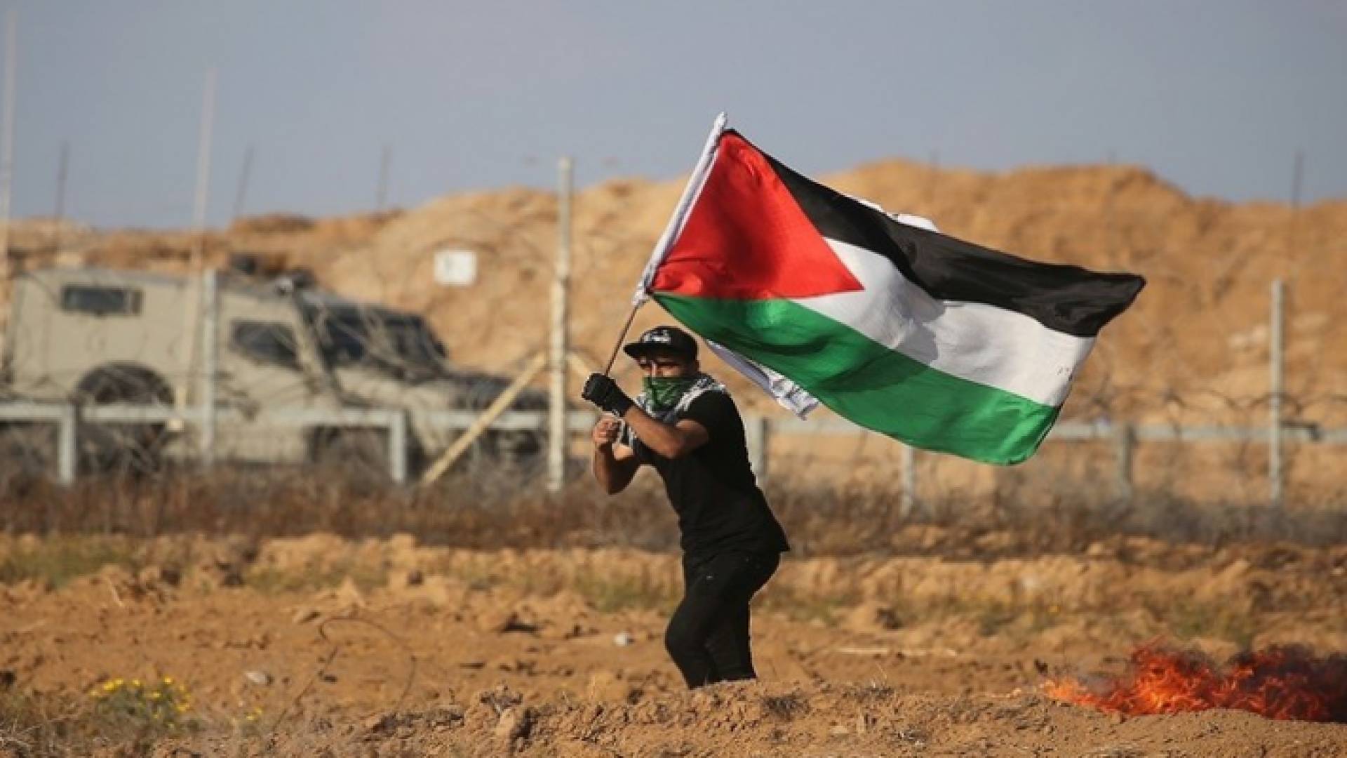 شاب فلسطيني يرفع علم بلاده