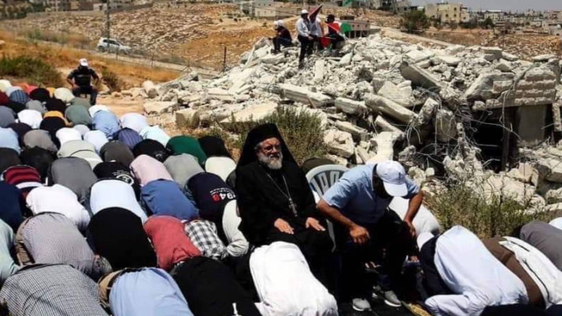 الأب عبد الله يوليو يجلس بين المصلين الذين يؤدون صلاة الجمعة